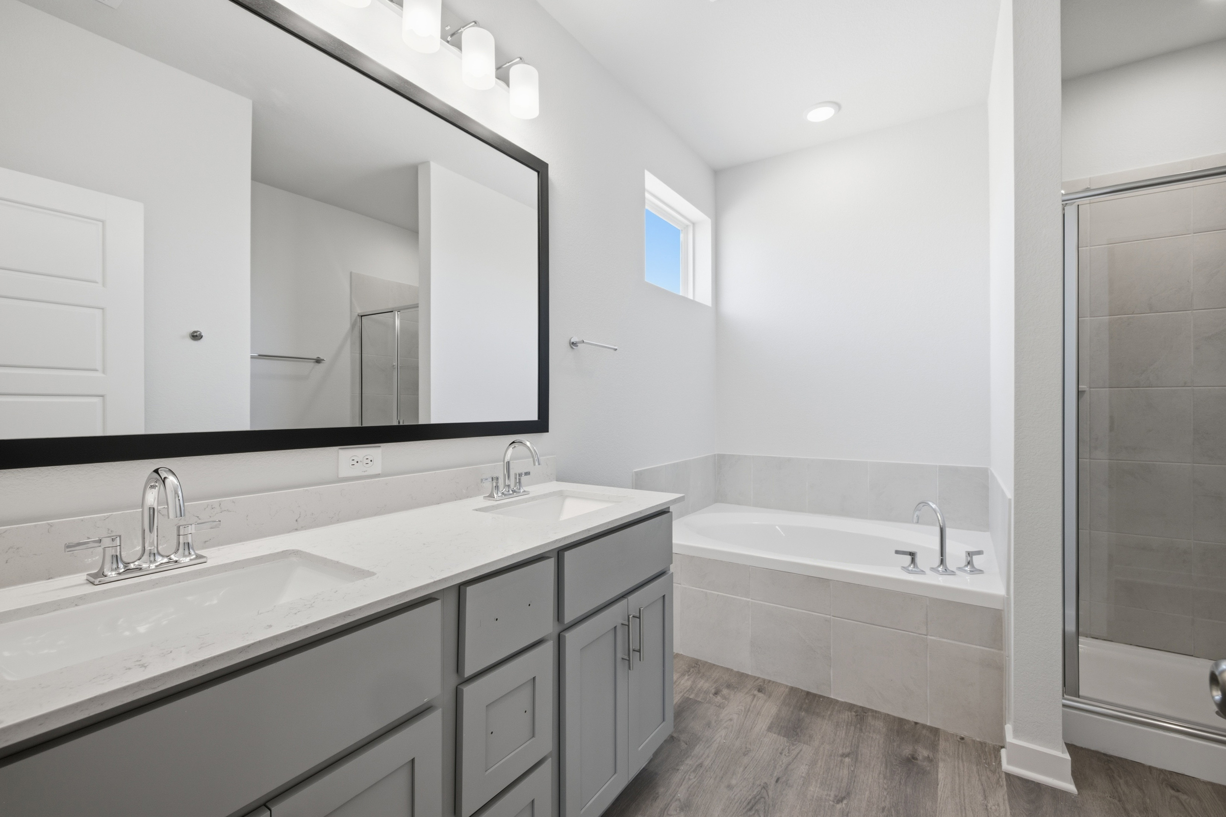 A bathroom with a tub sink and a mirror.