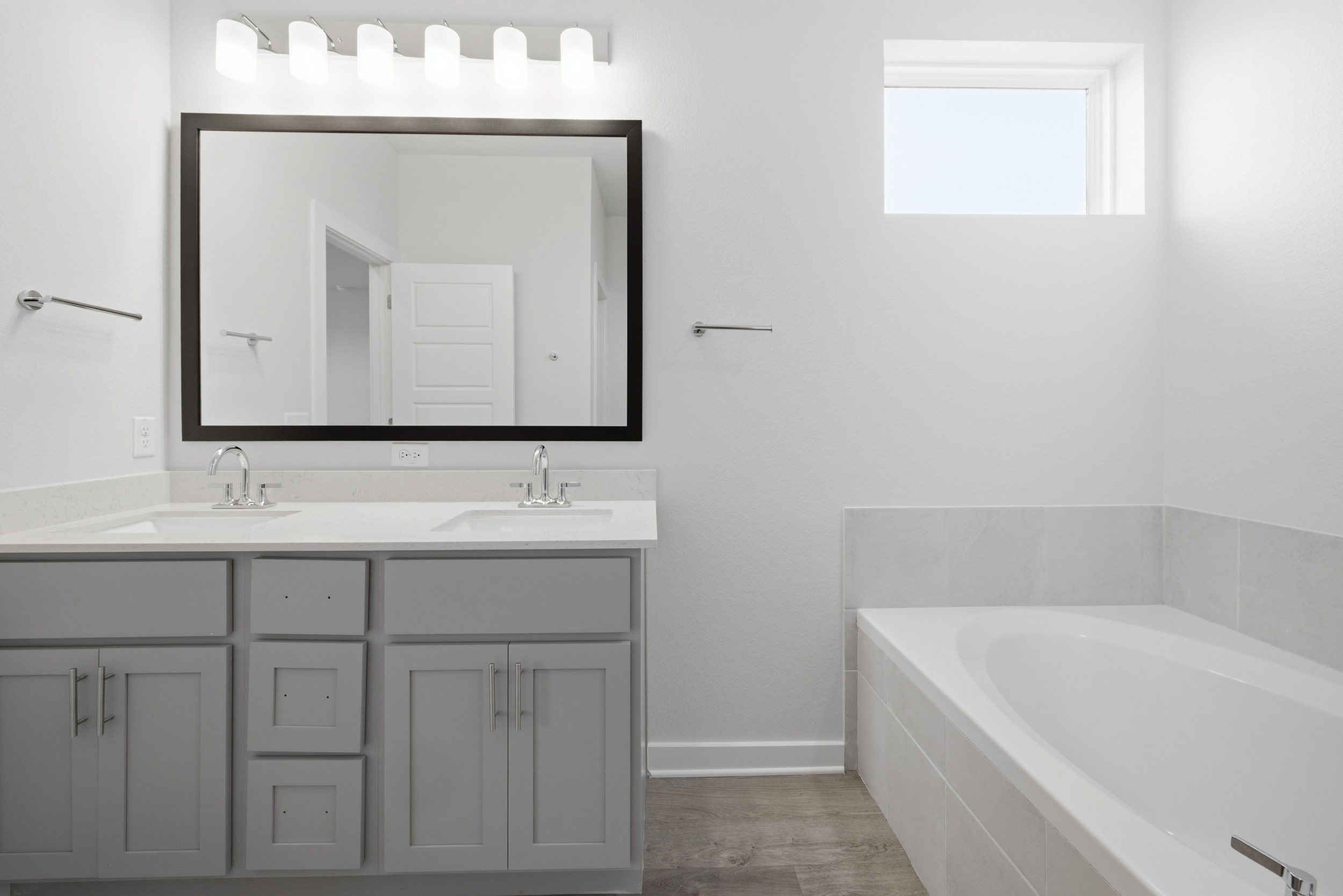 A bathroom with a tub sink and mirror.