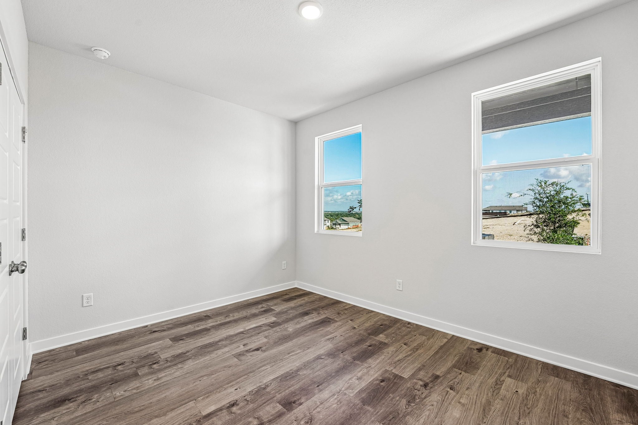 A room with a wood floor and a window with a view of the ocean.