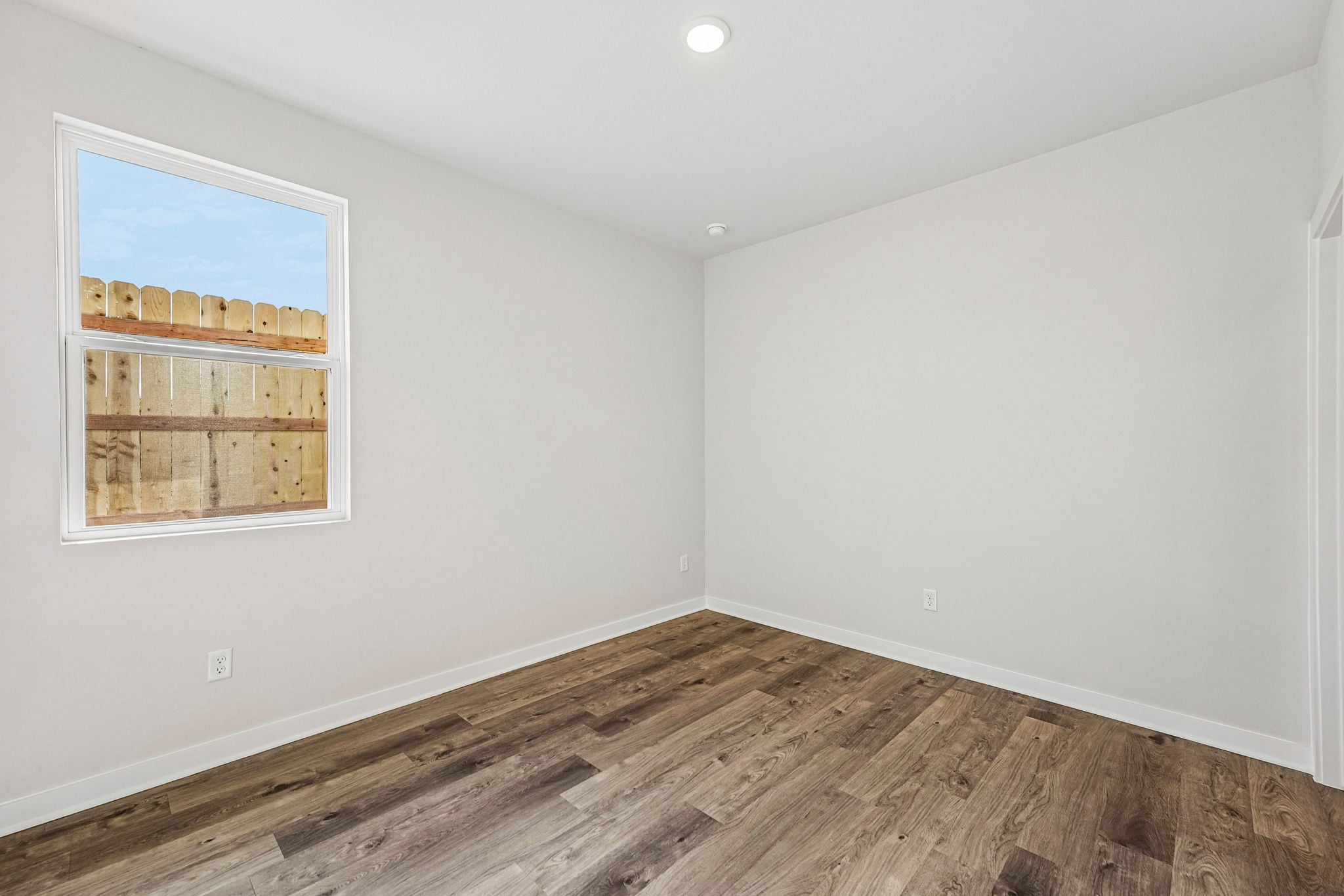 A room with a wood floor and a window with a wood floor.
