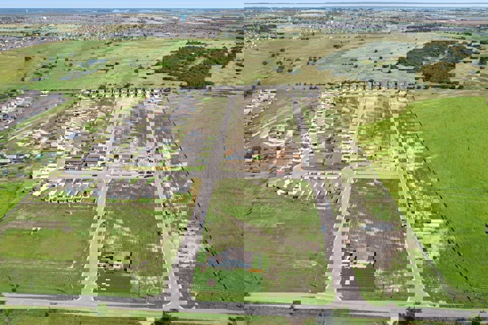 A road with a white building and grass on the side.