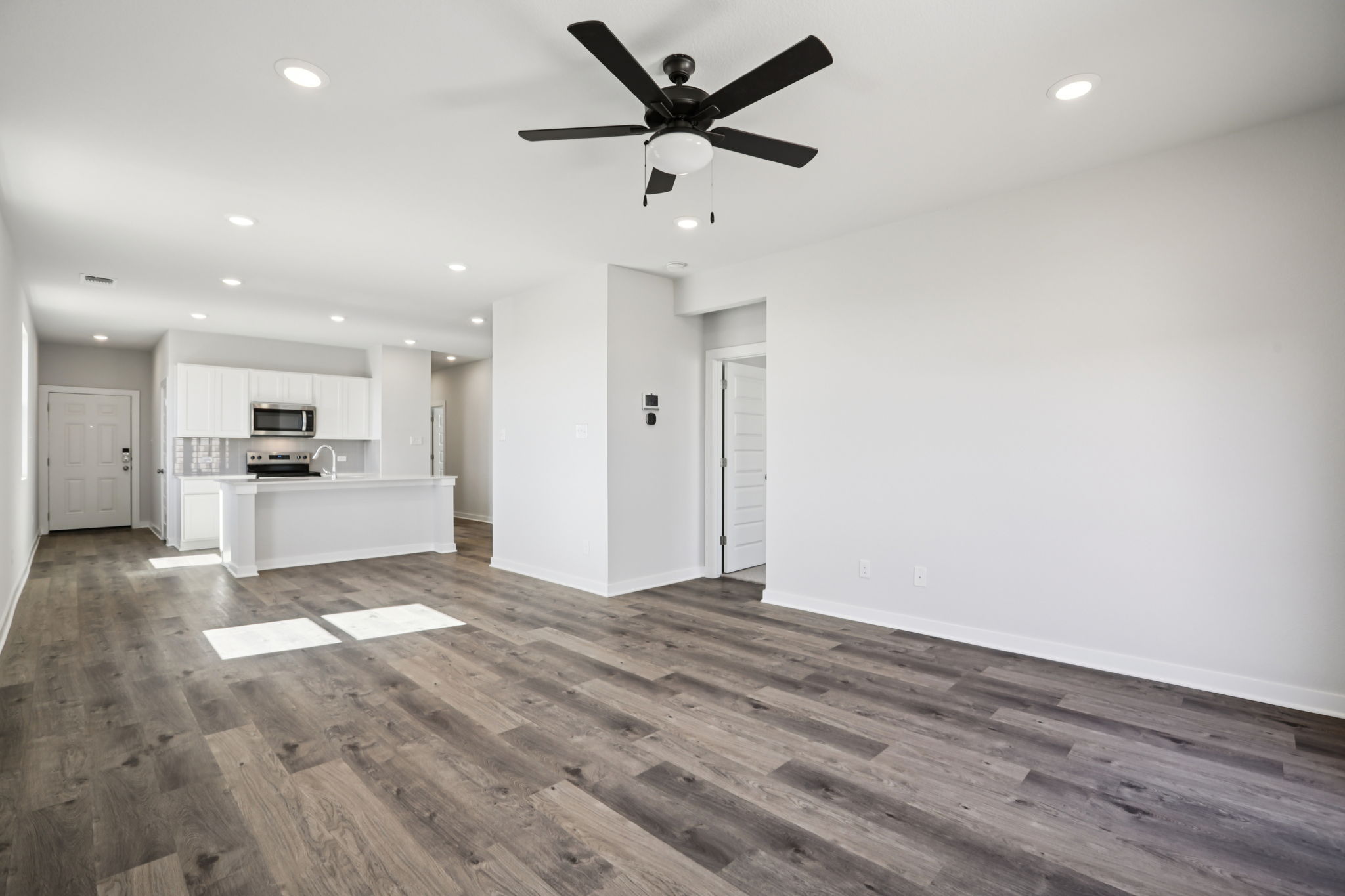 A large empty room with a ceiling fan and a wood floor.