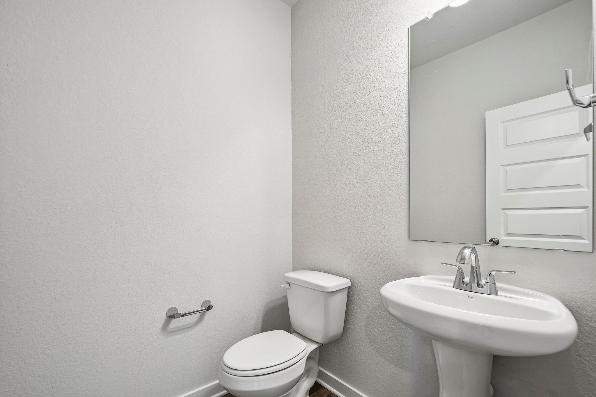 A bathroom with a sink toilet and mirror.