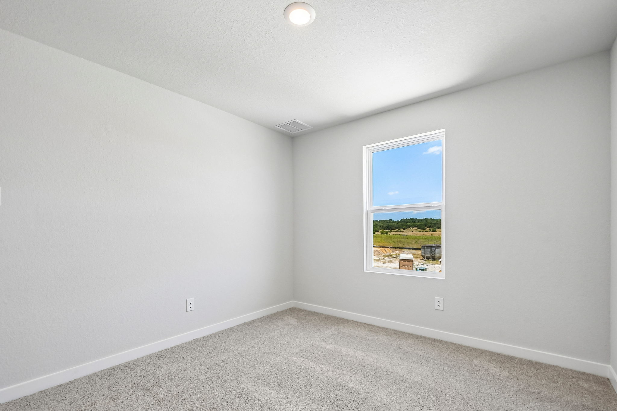 A room with a window and a view of a field.