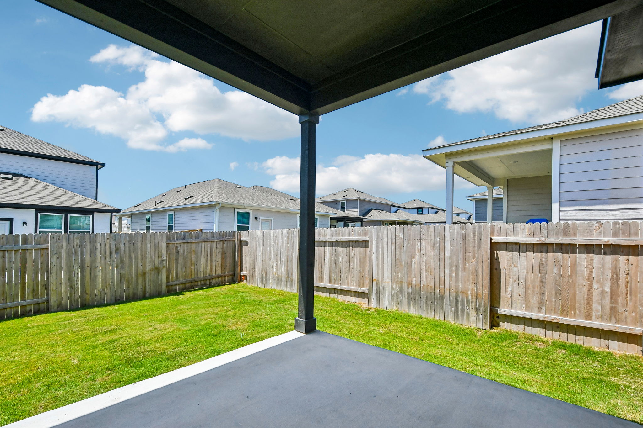A fenced in yard with a wooden gate and a building in the background.
