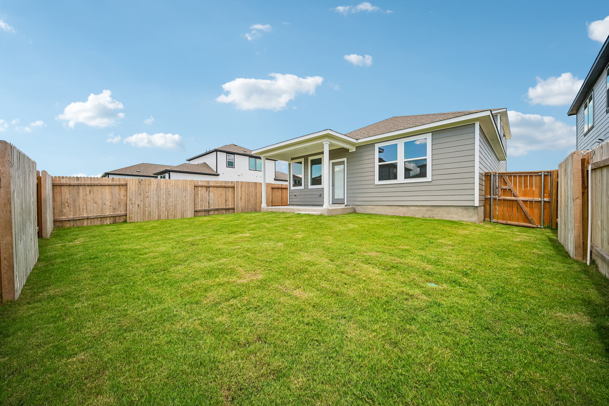 A fenced in yard with a house in the background.