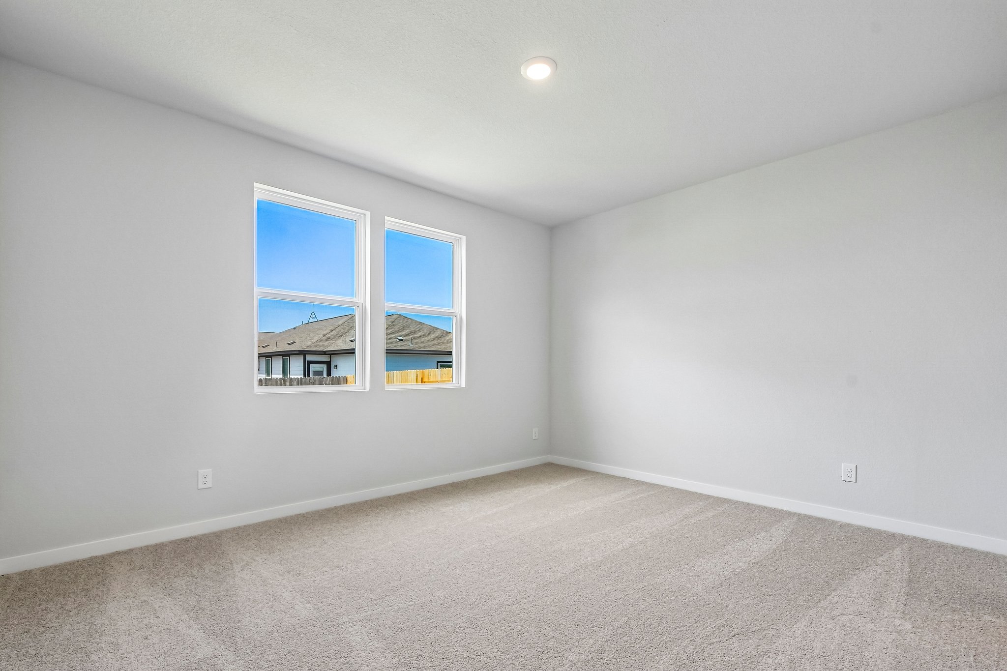 A room with a window and a white wall with a painting on it.