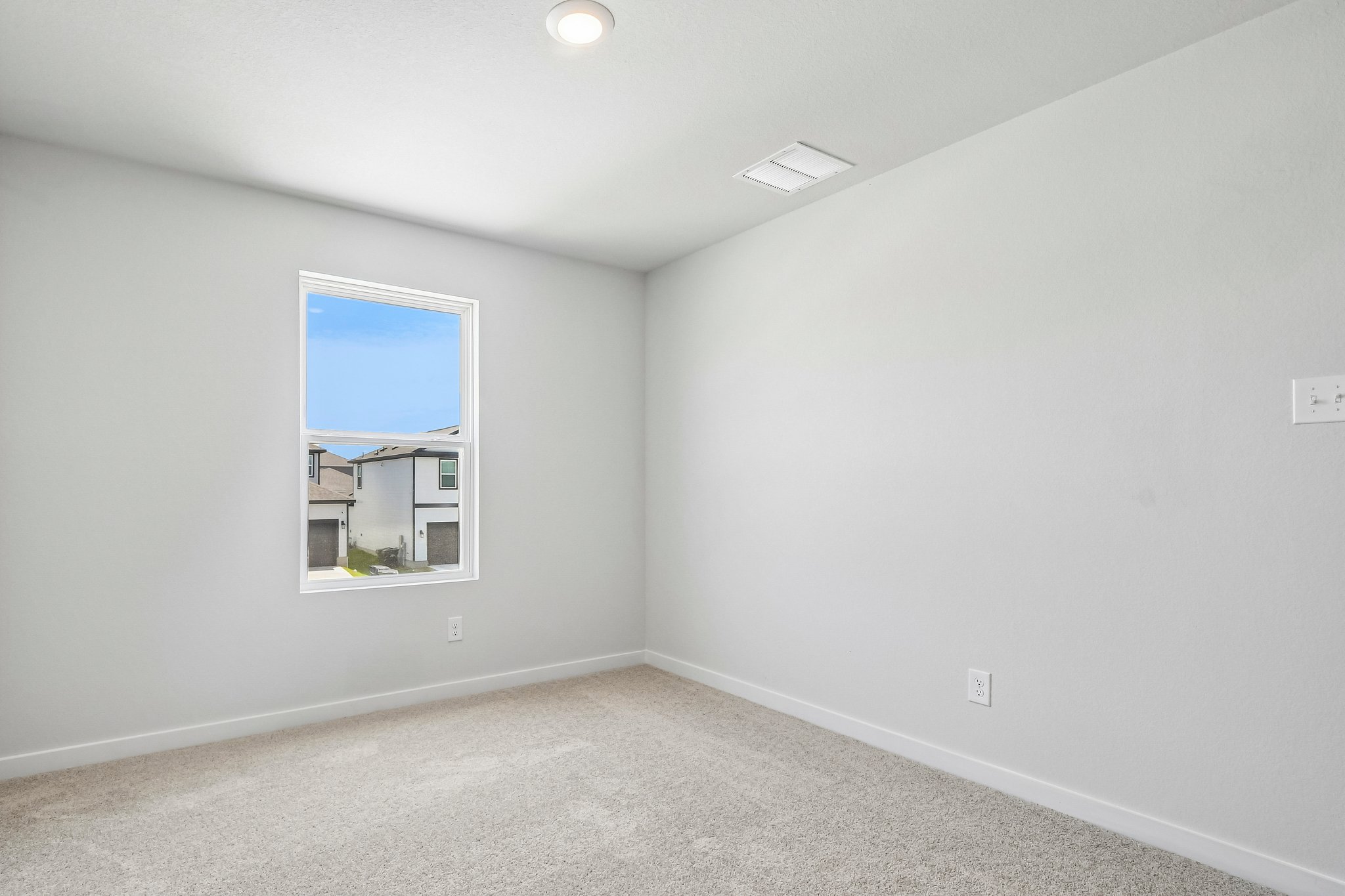 A room with a window and a light on the wall.