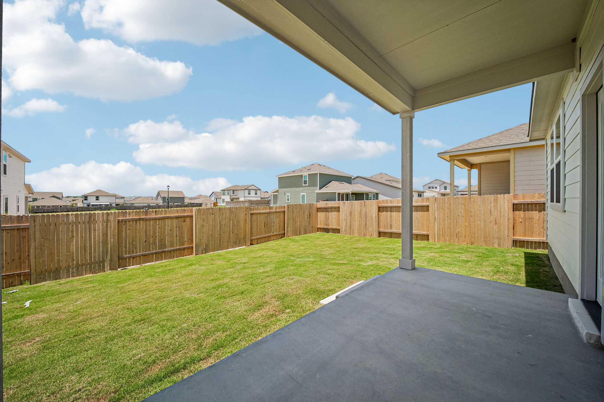 A fenced in yard with a house and a walkway.