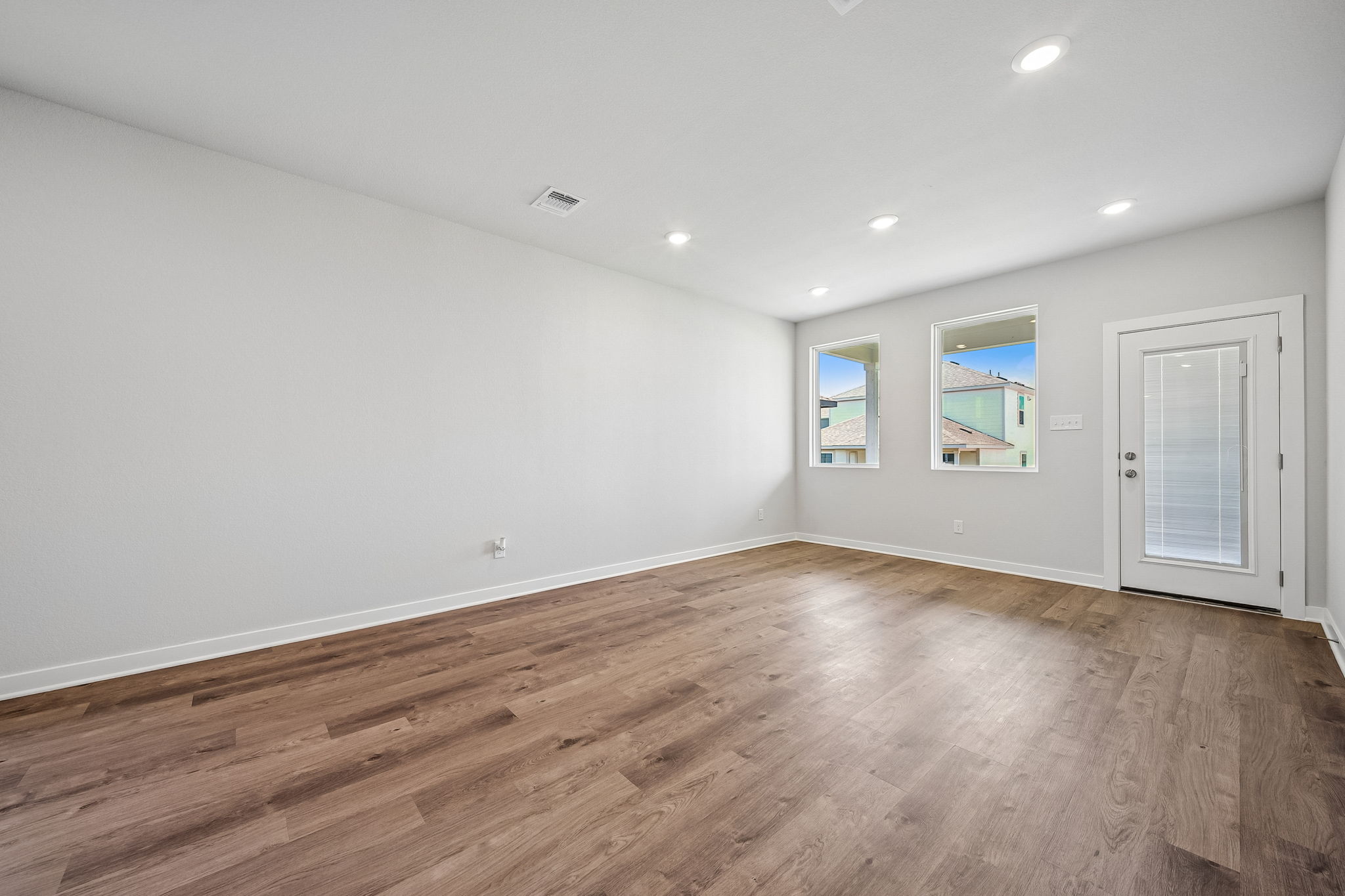 A room with a wood floor and a wood floor with a white door.