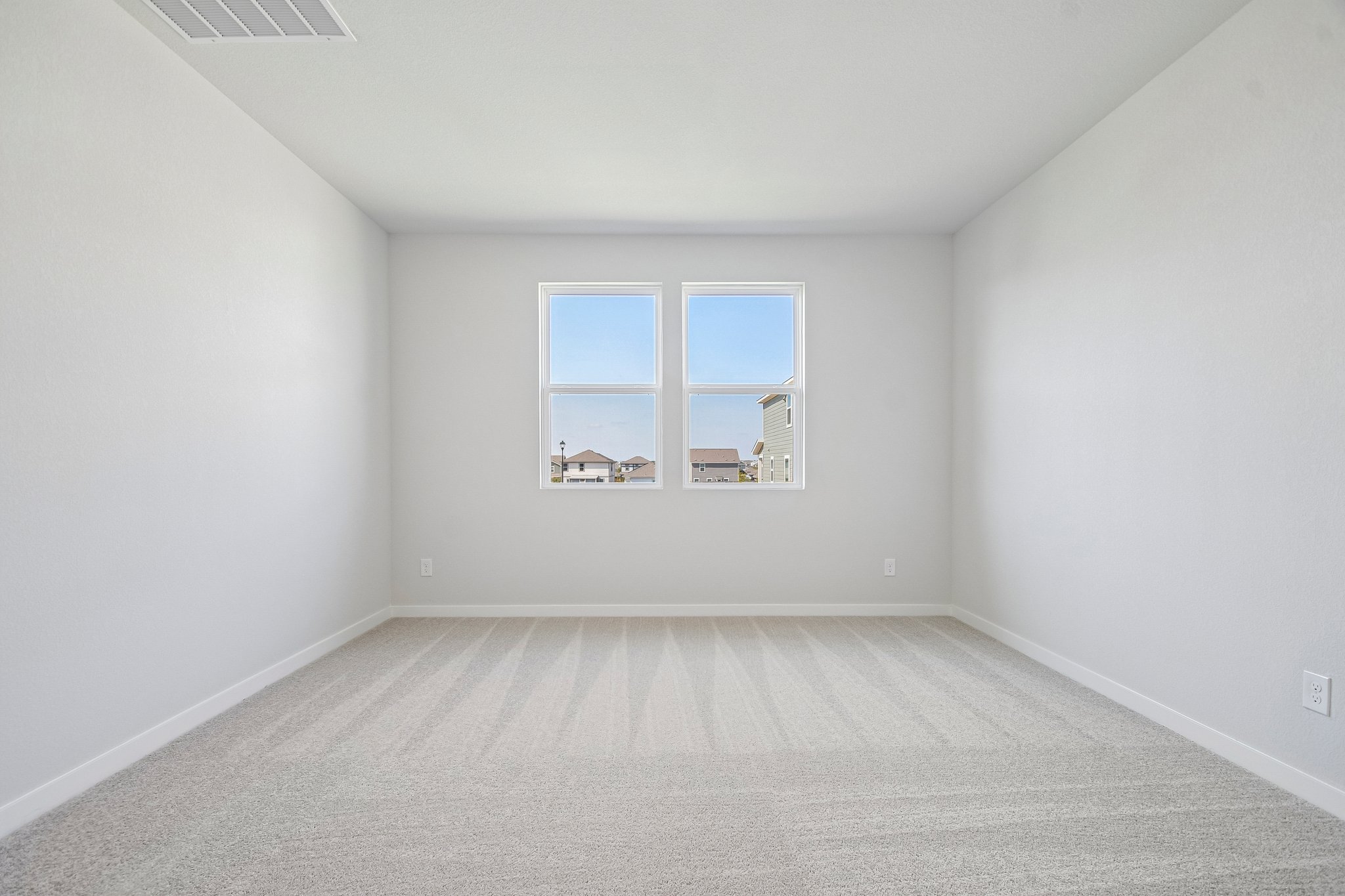 A room with a window and a white wall.