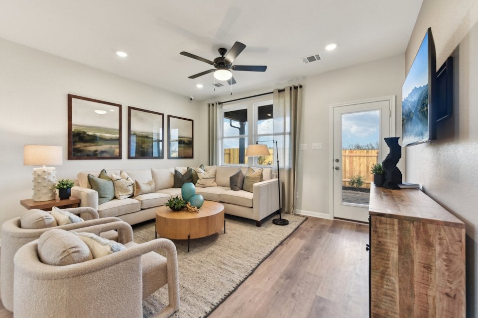 A living room with a large white couch and a wood floor.