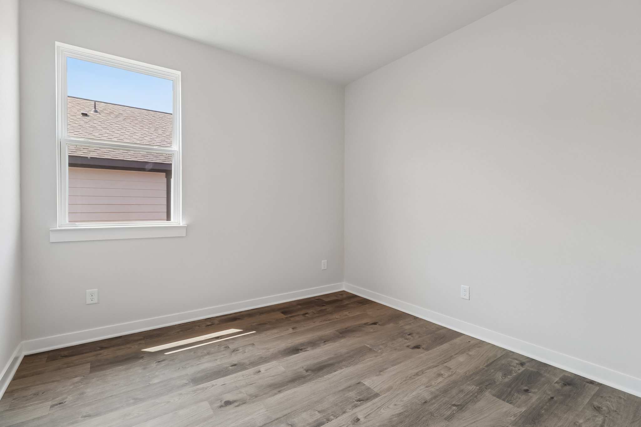 A room with a wood floor and a window.