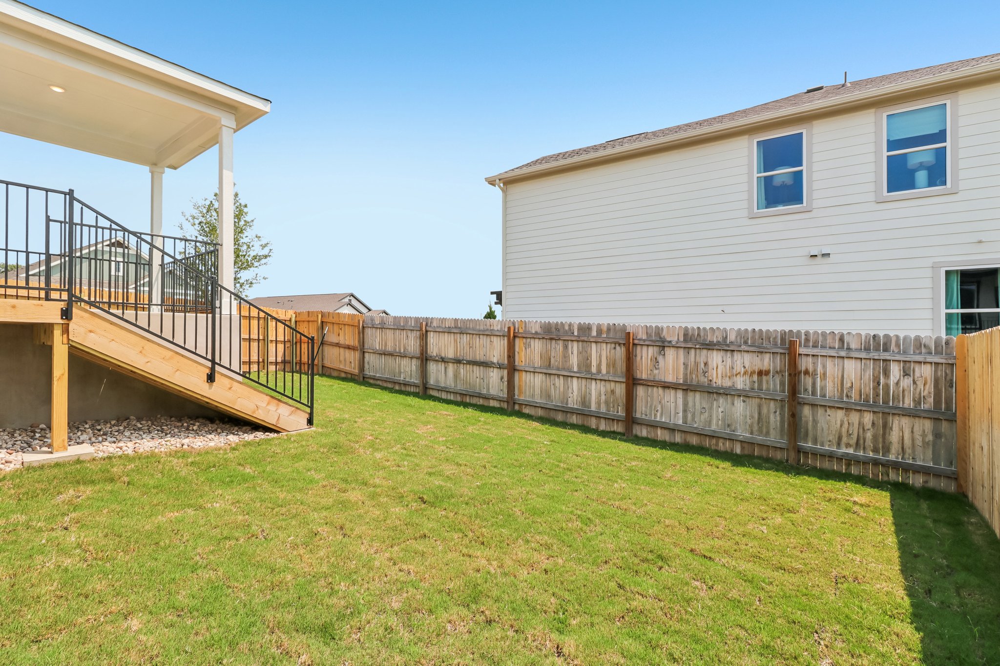A fenced in yard with a house and a deck.