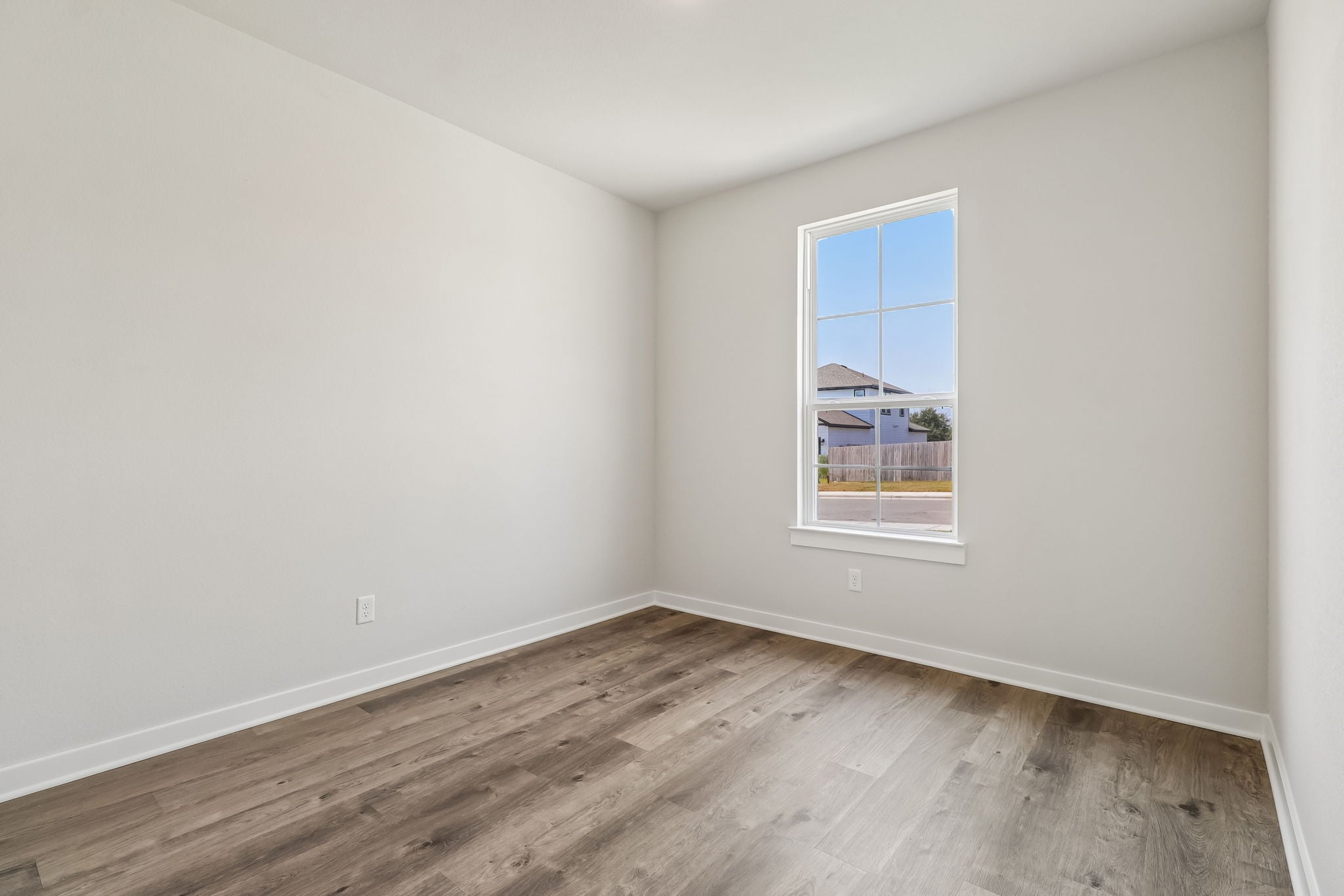 A room with a wood floor and a window with a view of a city.