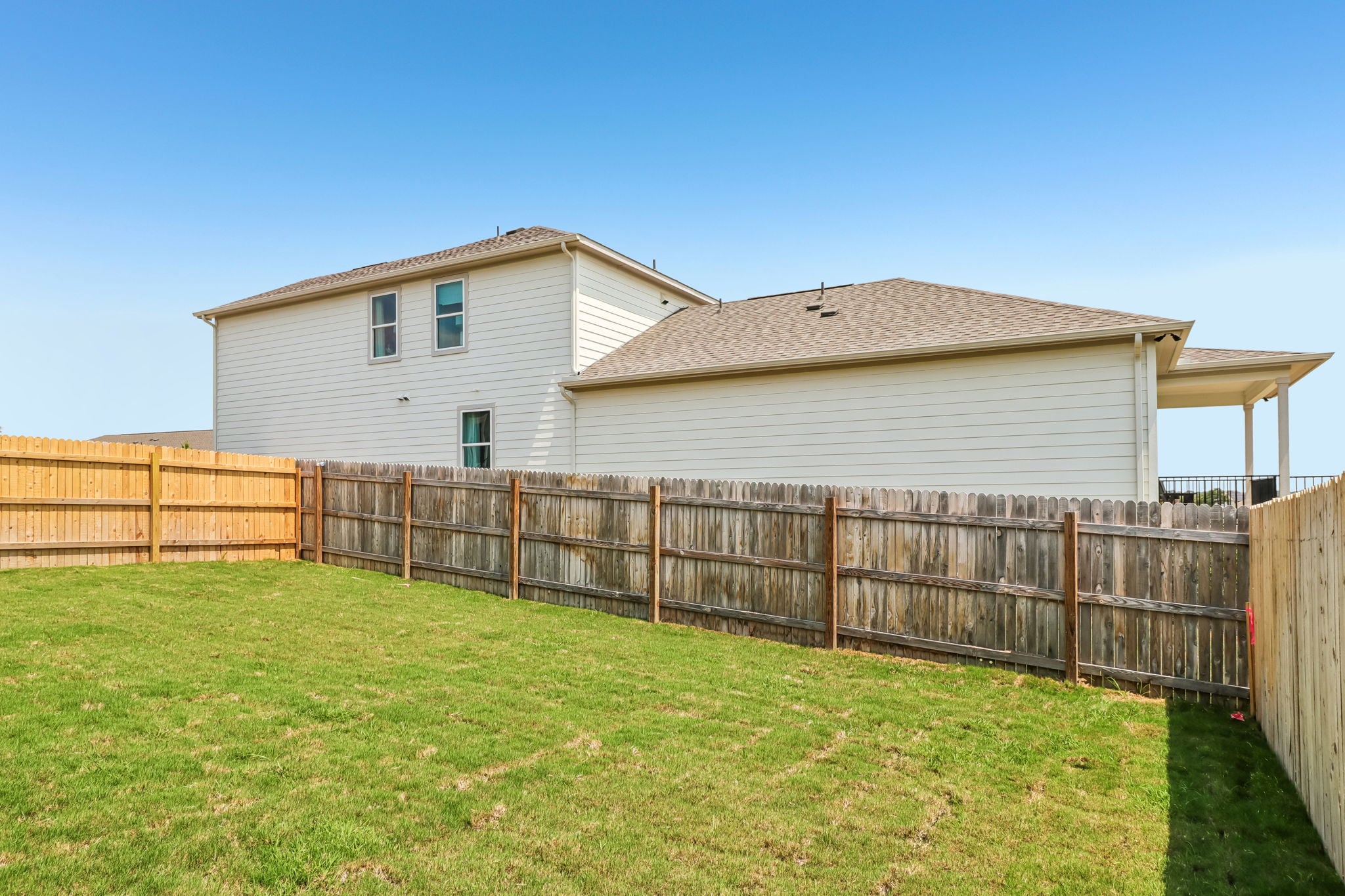 A fenced in yard with a house in the background.