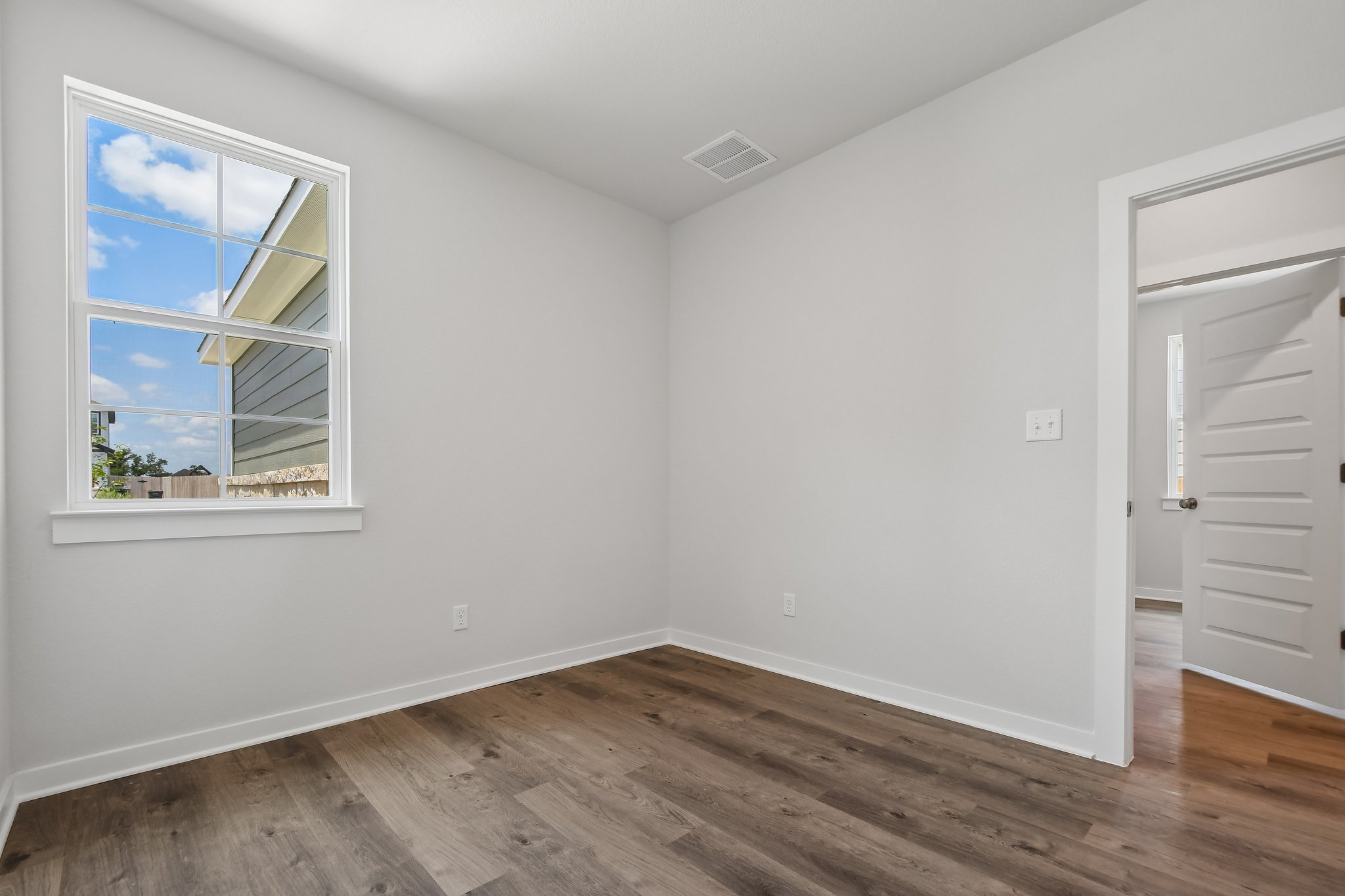 A room with a wood floor and a window with a wood floor.