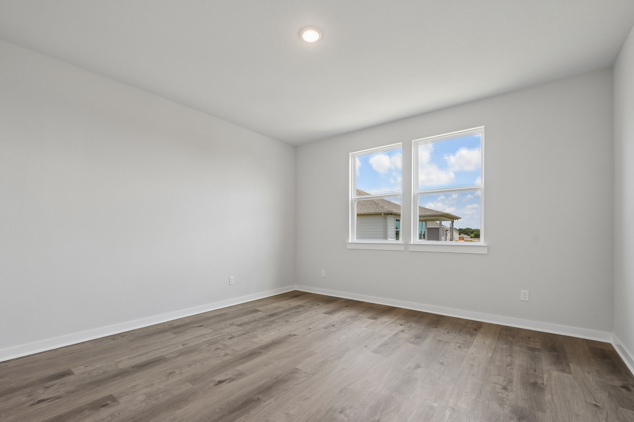 A room with a wood floor and a window with a view of the city.
