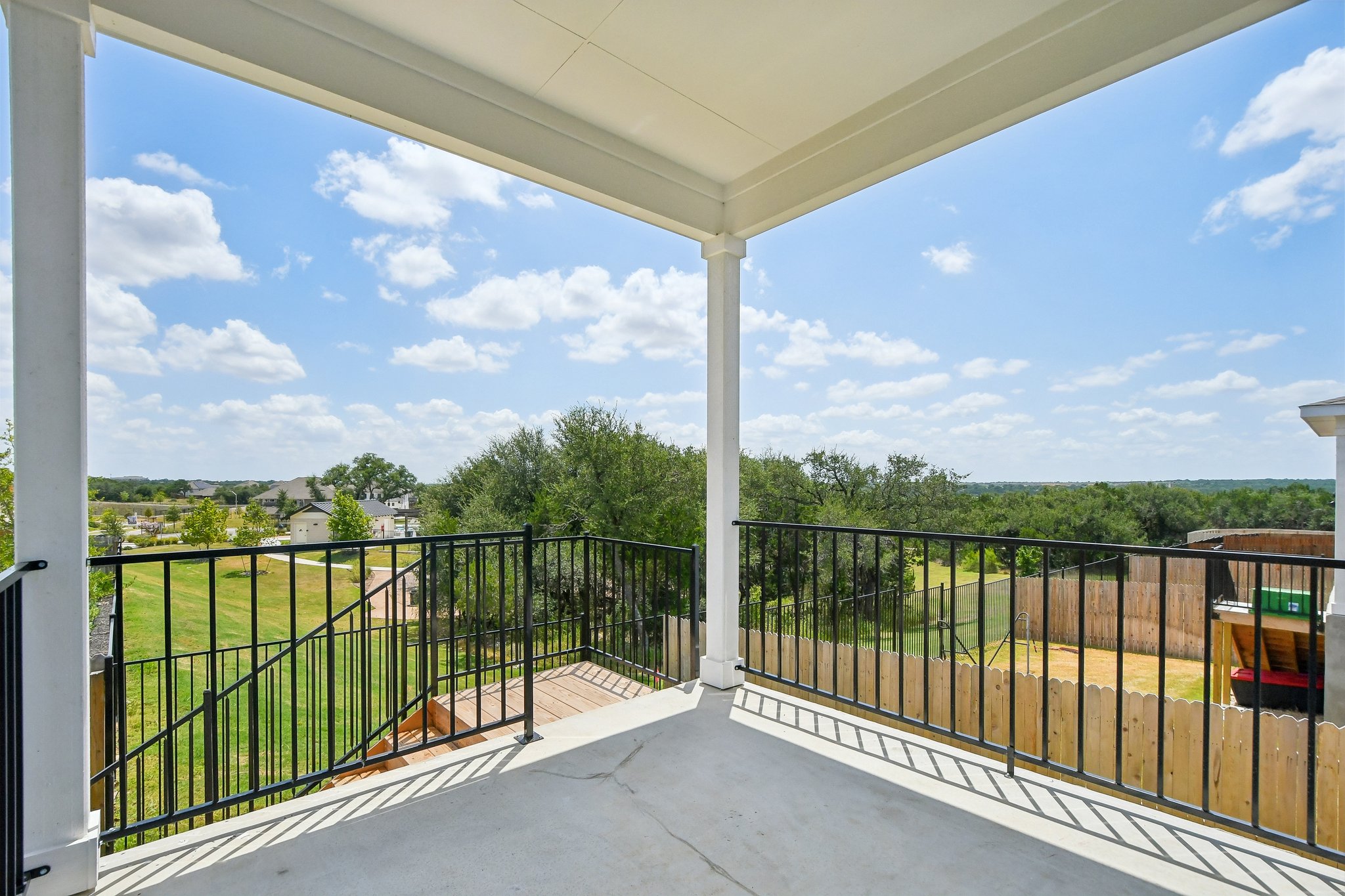 A view of a balcony with trees and blue sky.