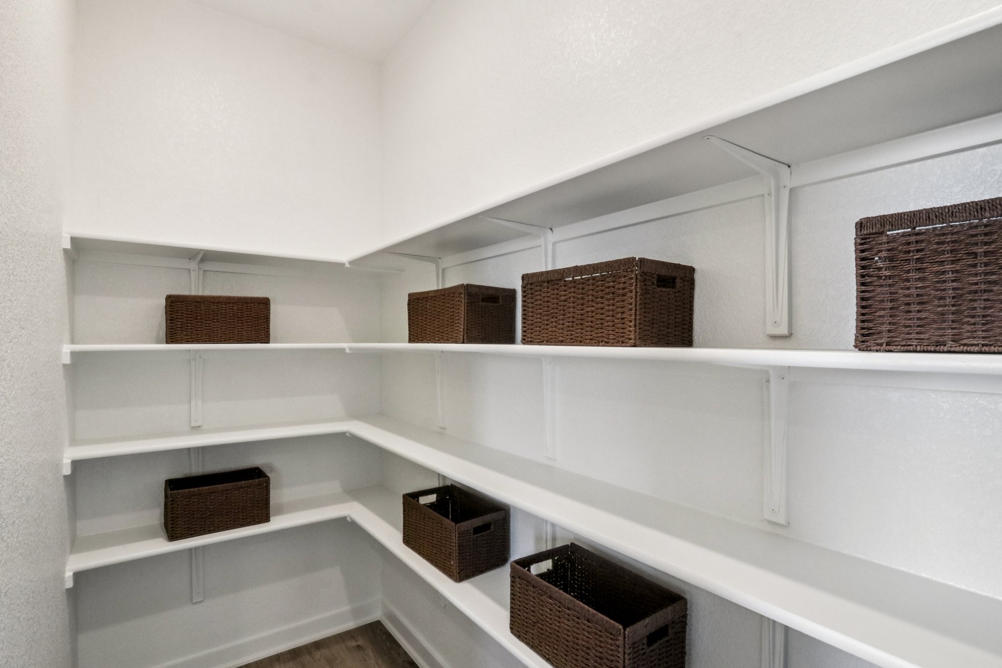 A white shelf with baskets on it.
