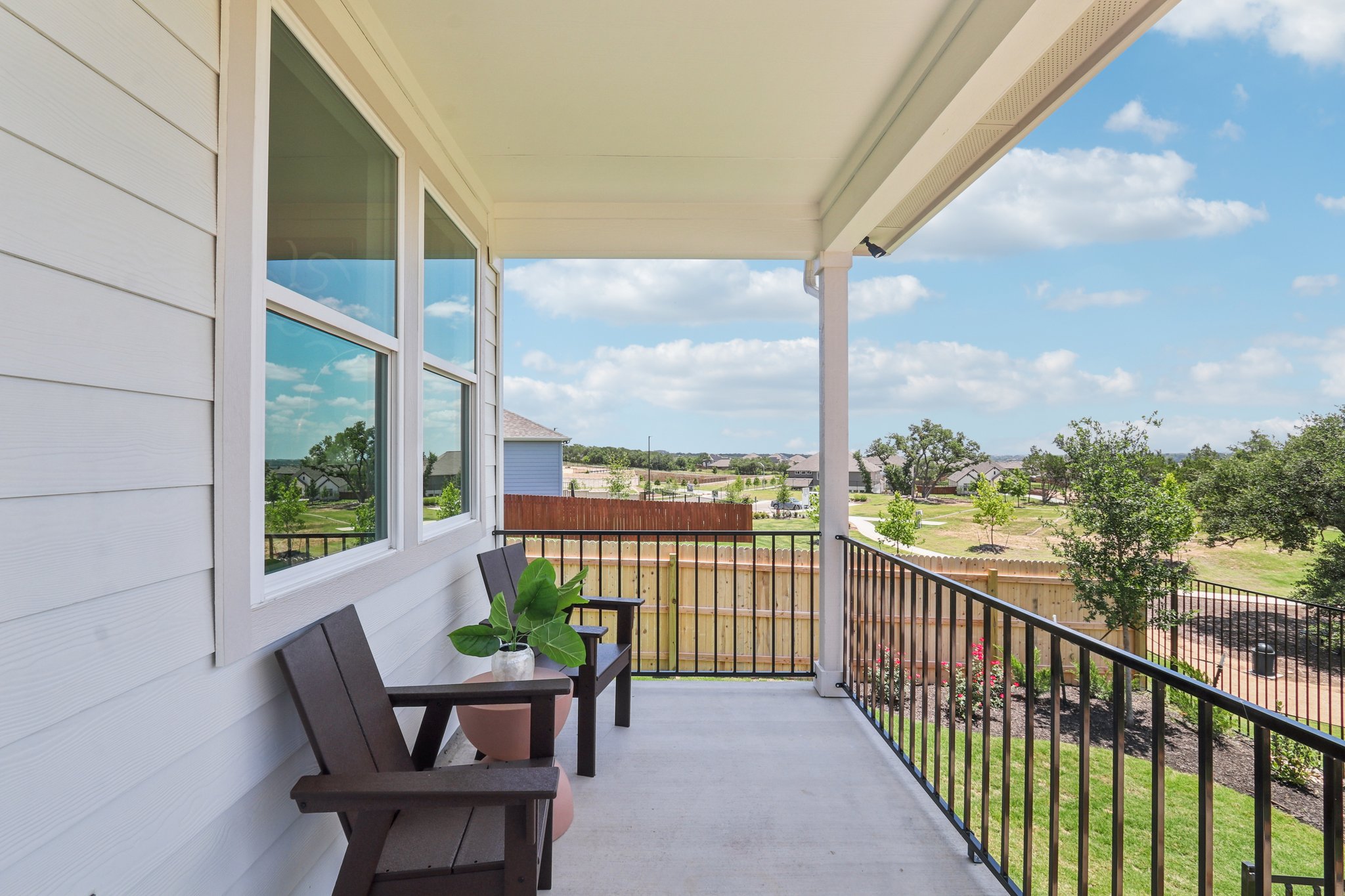 A deck with a table and chairs on it and a view of trees and a building.