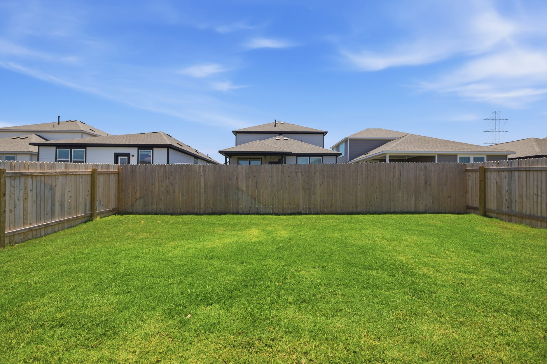 A fenced in yard with a house in the background.