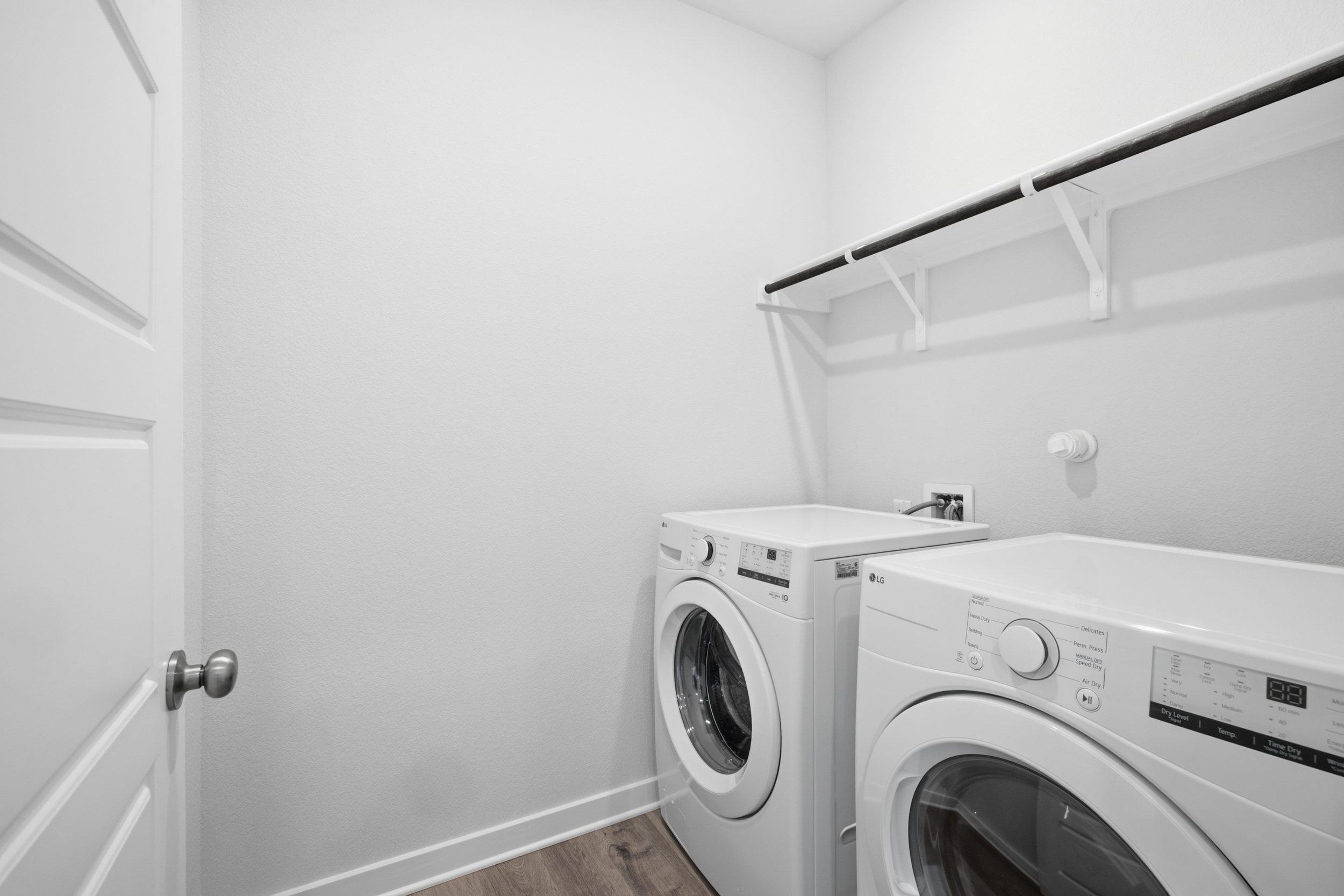 A white laundry room with a white laundry machine and a white door.