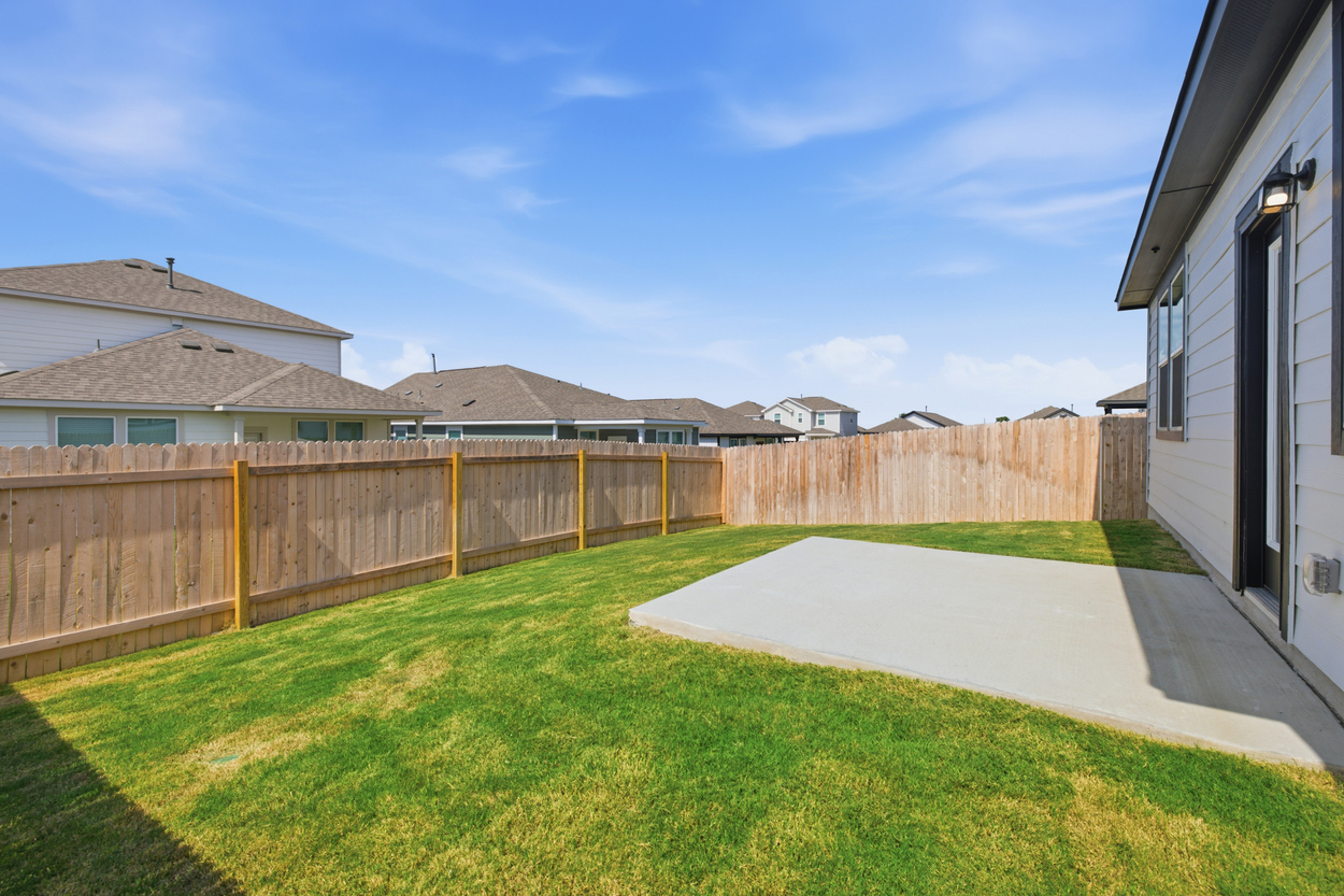 A fenced in yard with a house and a driveway.