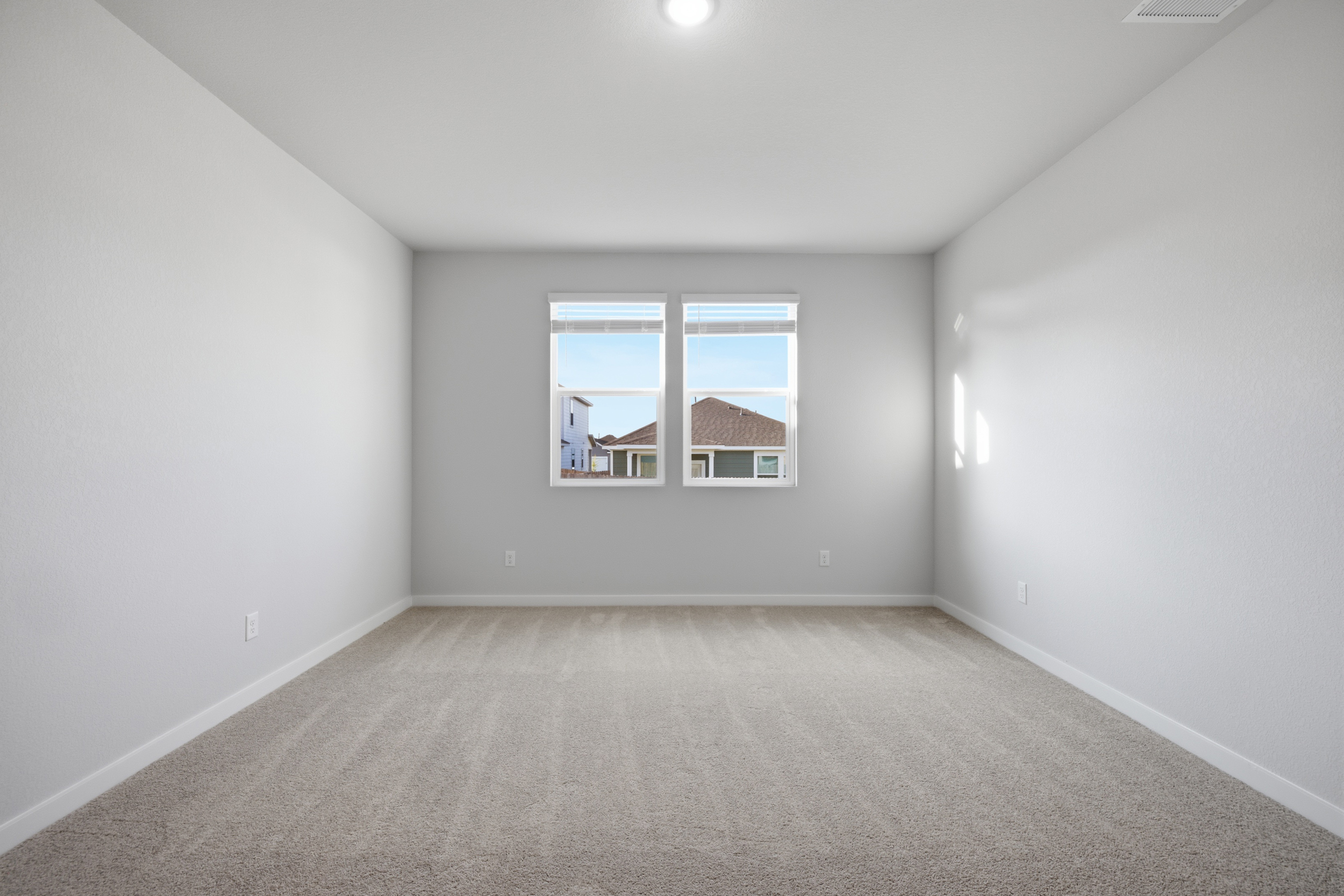 A room with a window and a white wall.