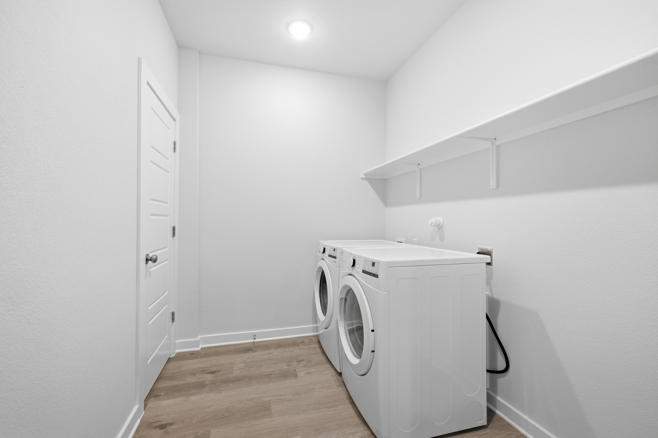 A white room with a washing machine and a white door.