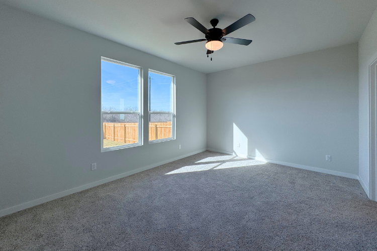 A room with a ceiling fan and a window with a view of the city.