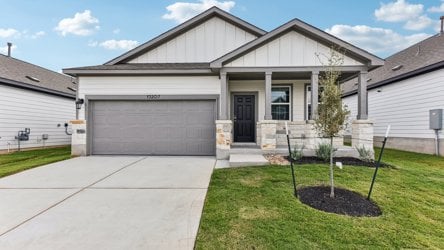 A house with a garage and a tree in the front.