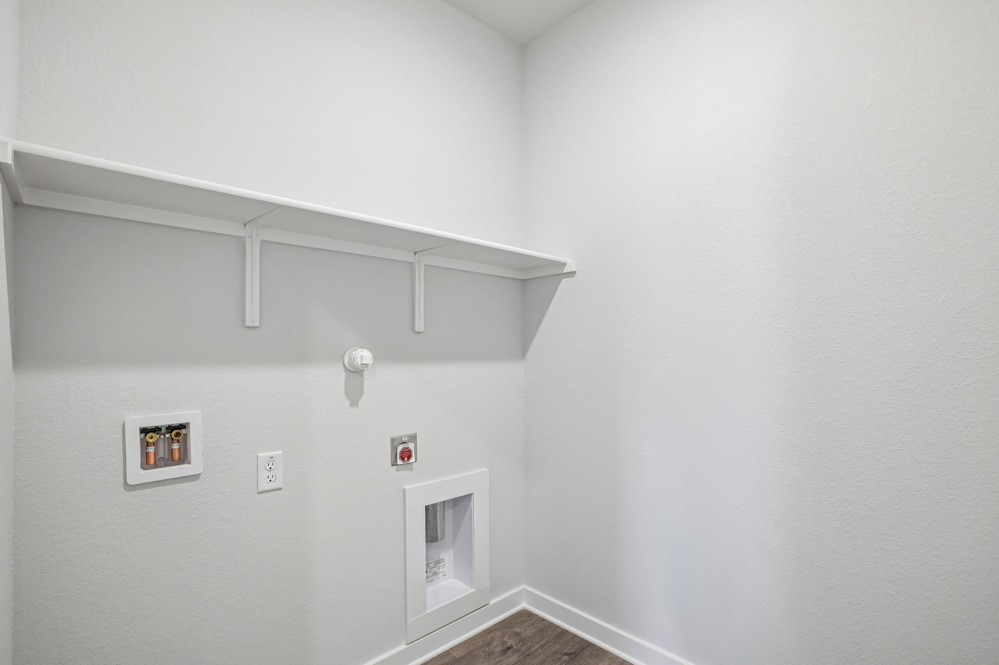 A white wall with a shelf and a light switch.