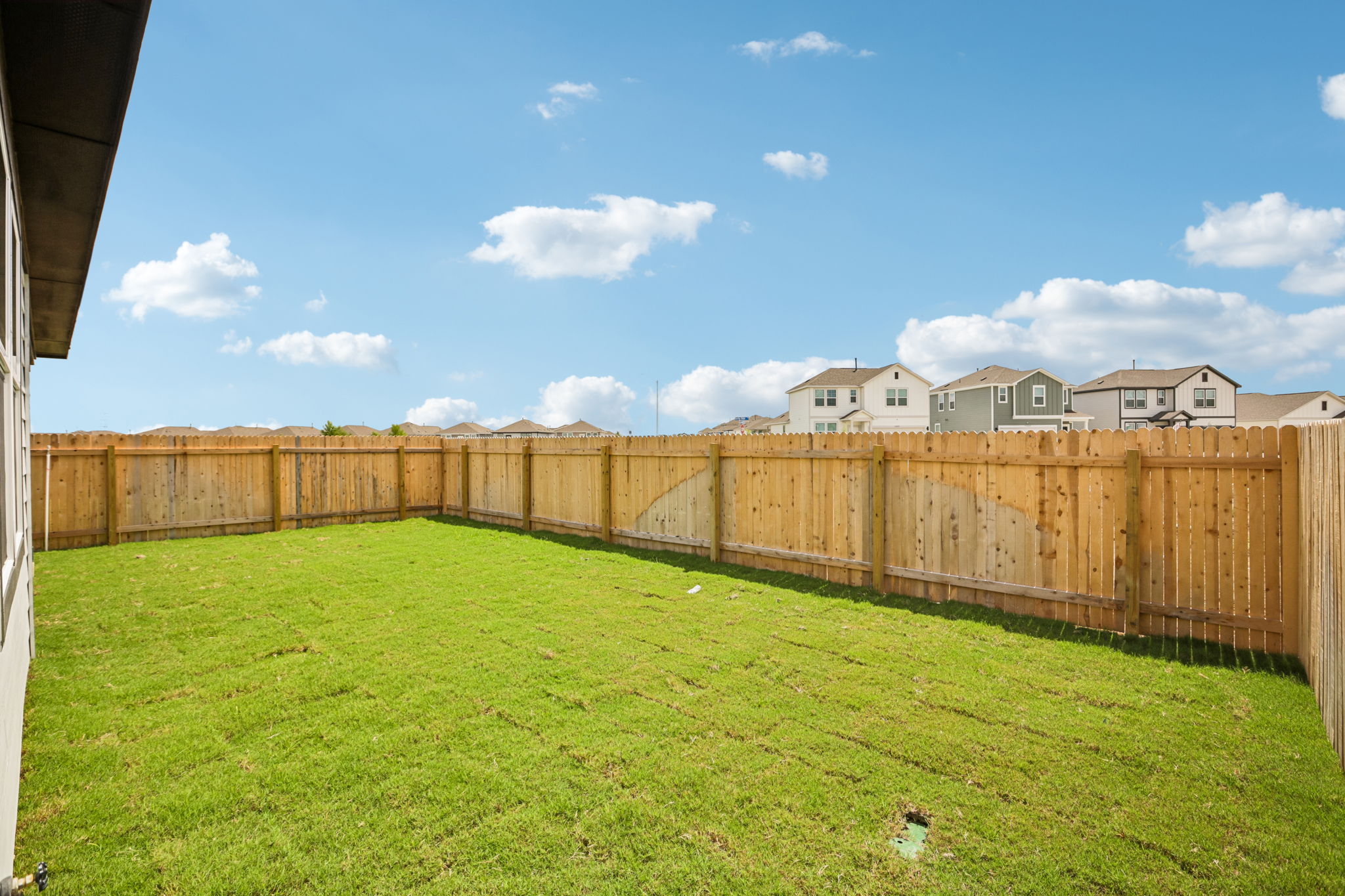 A fenced in yard with houses in the background.