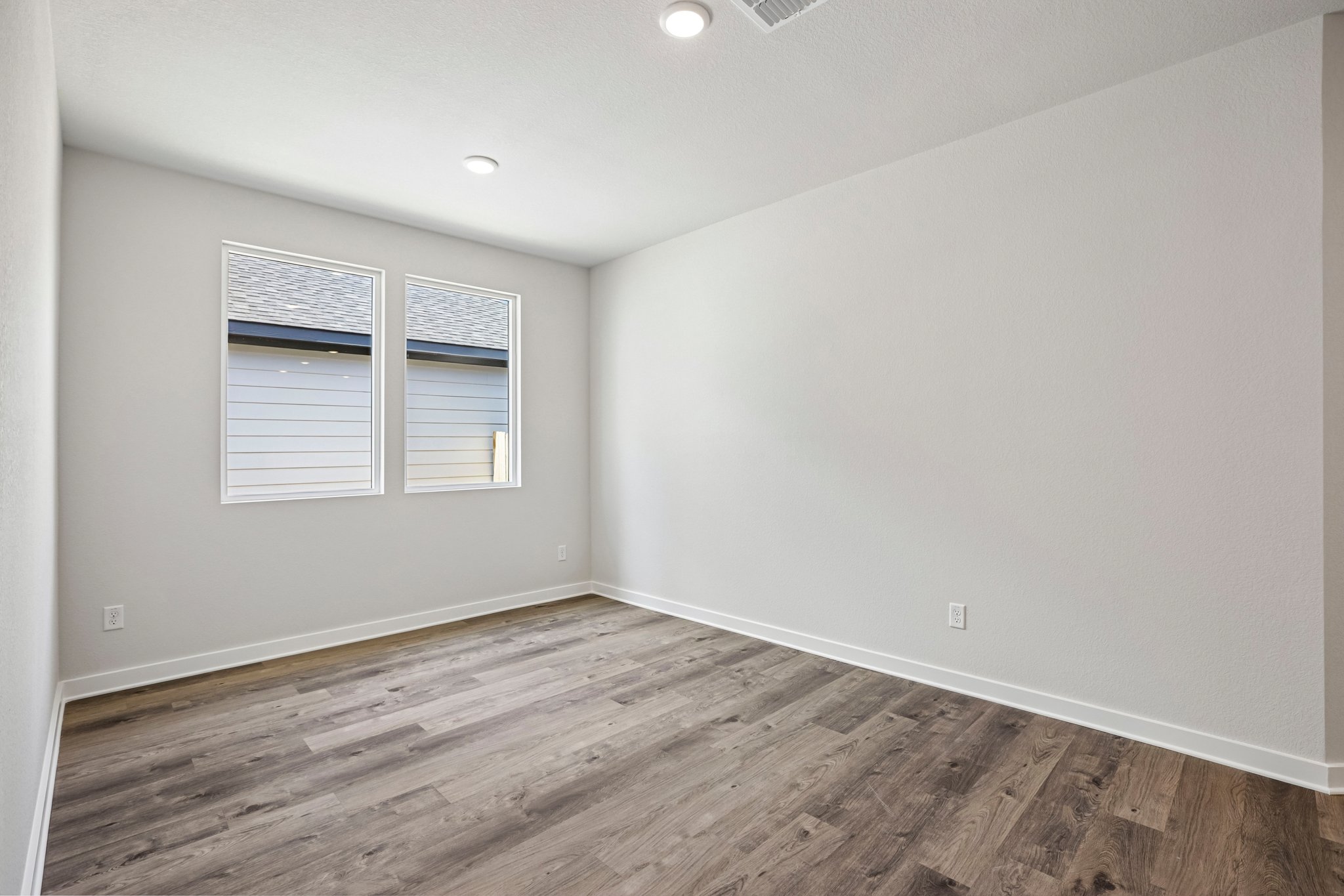 A room with a wood floor and a window with blinds.