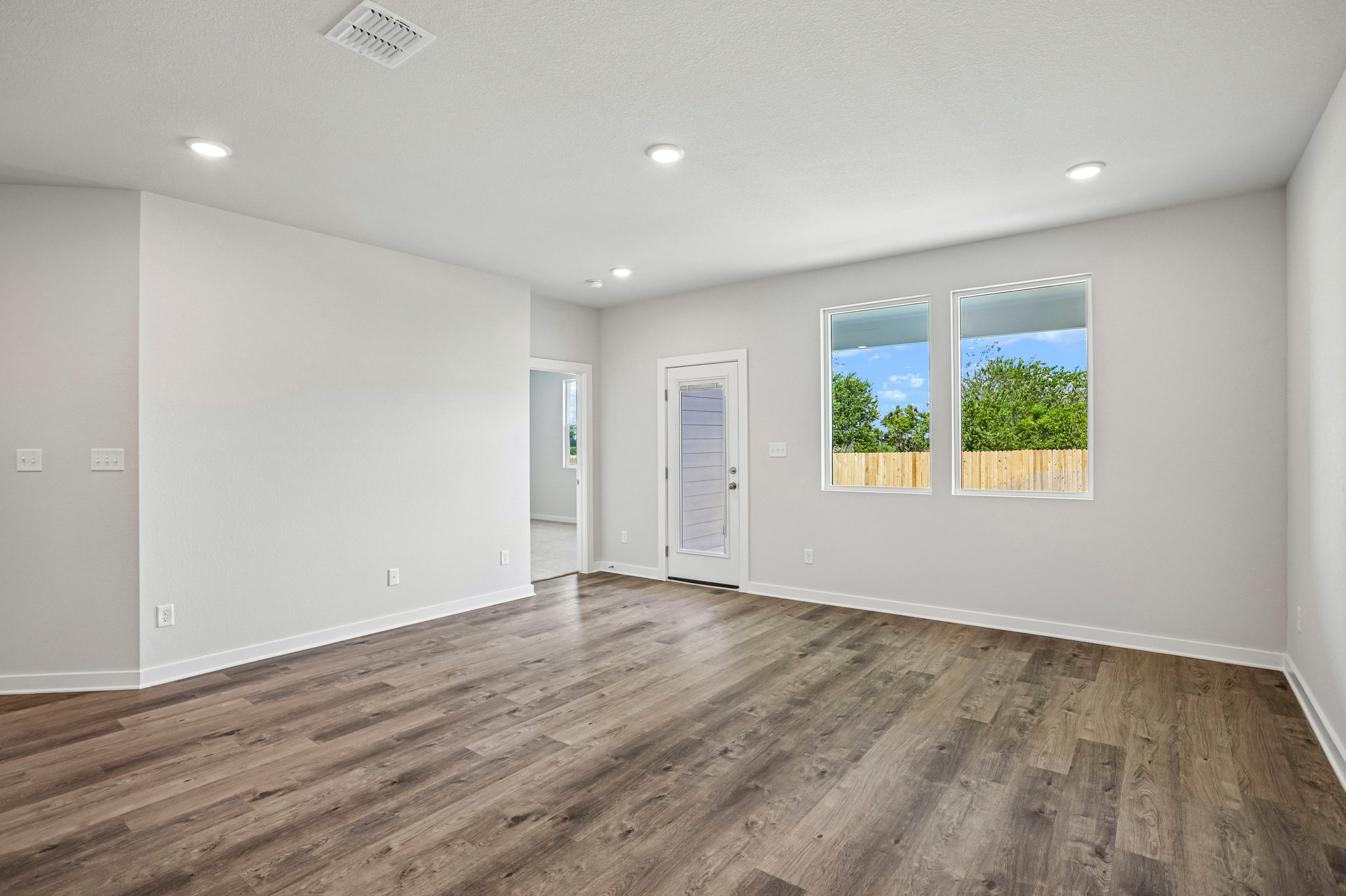 A room with a wood floor and windows.