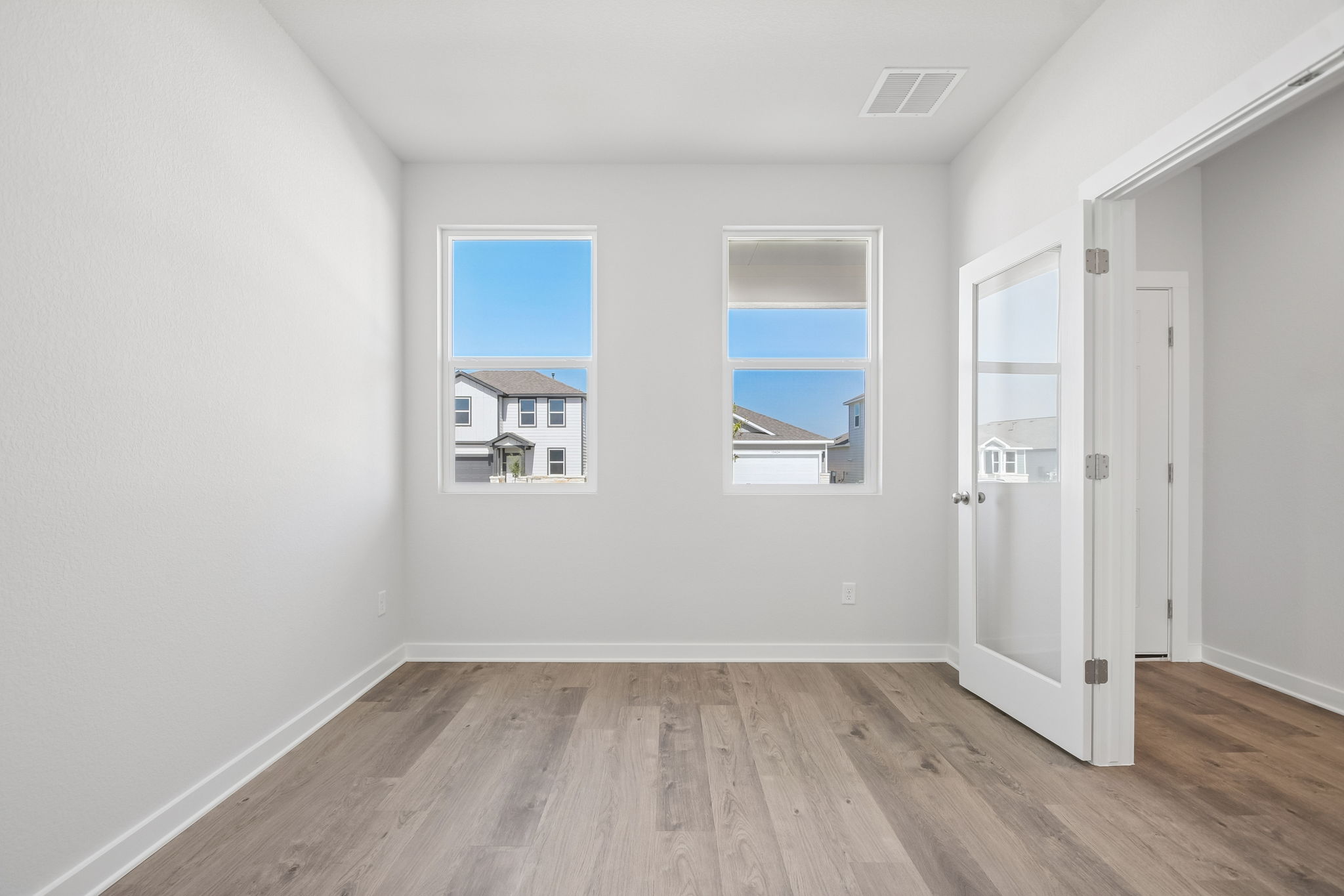 A room with white walls and a wood floor with a window and a wood floor with a wood.