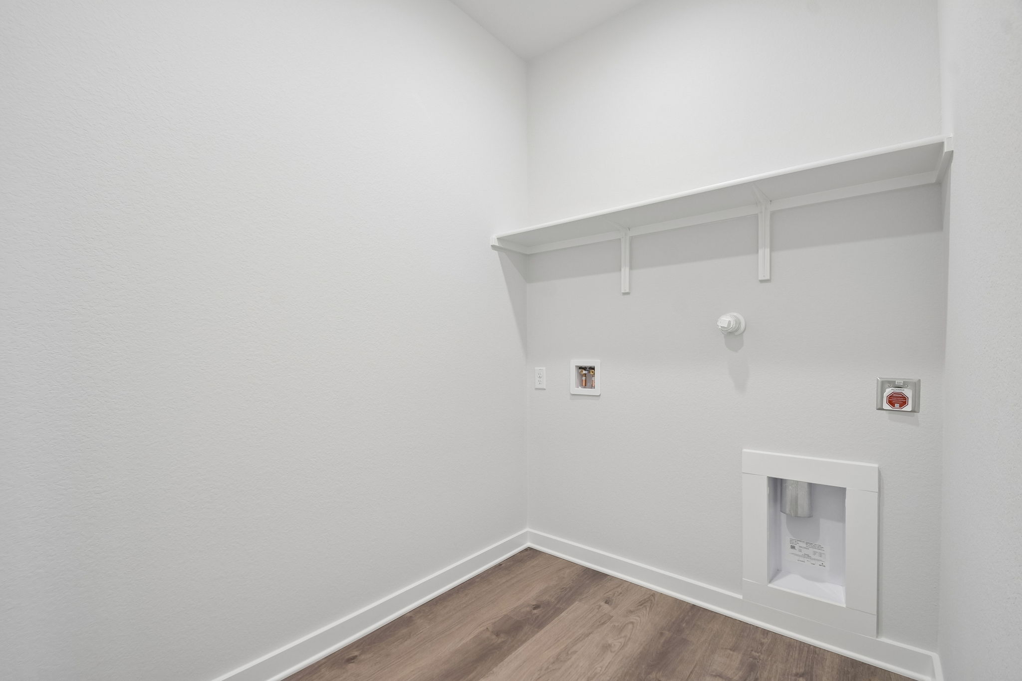 A white room with a wood floor and a white wall with a light.