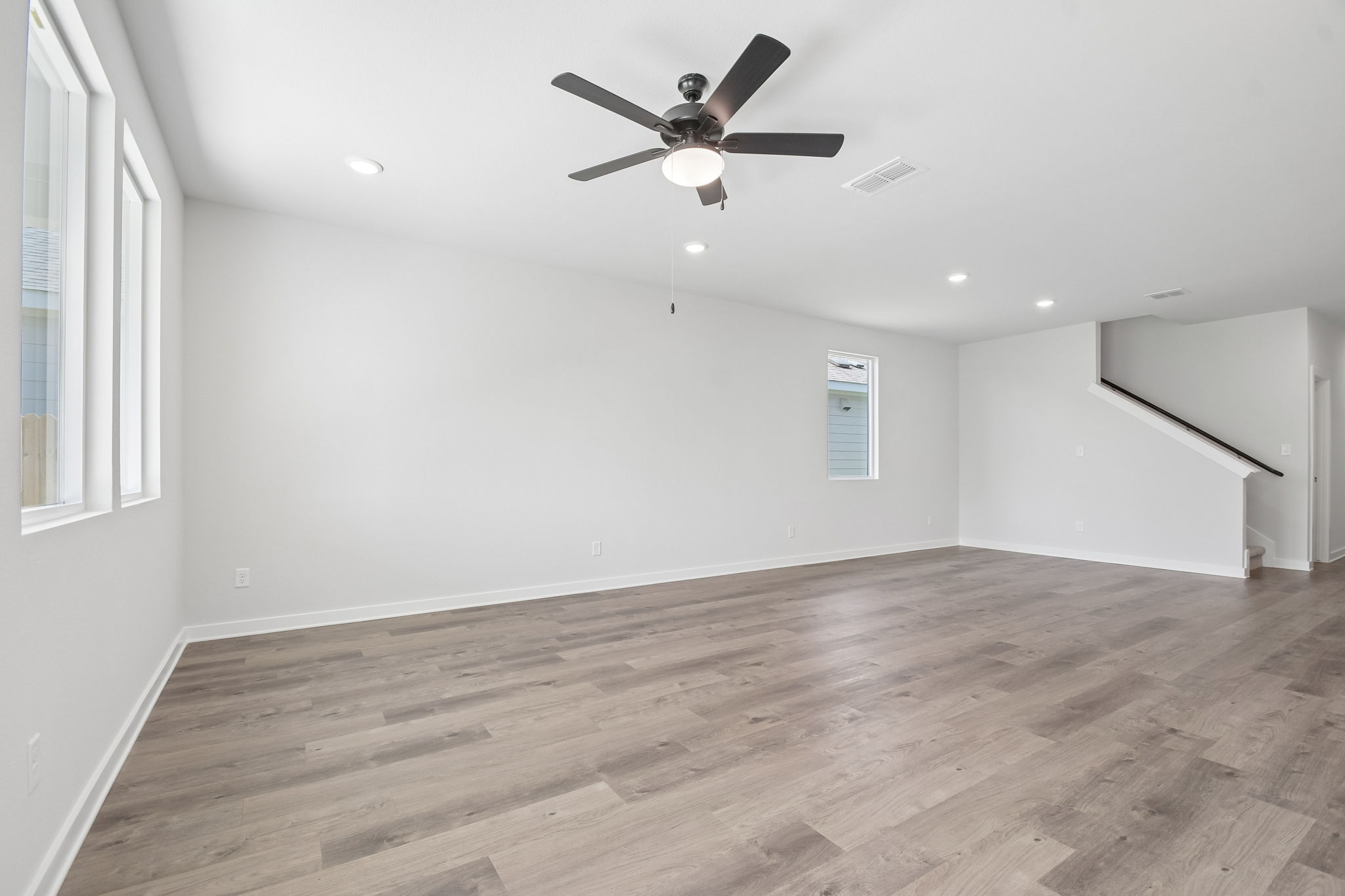 A room with a ceiling fan and wood floor.