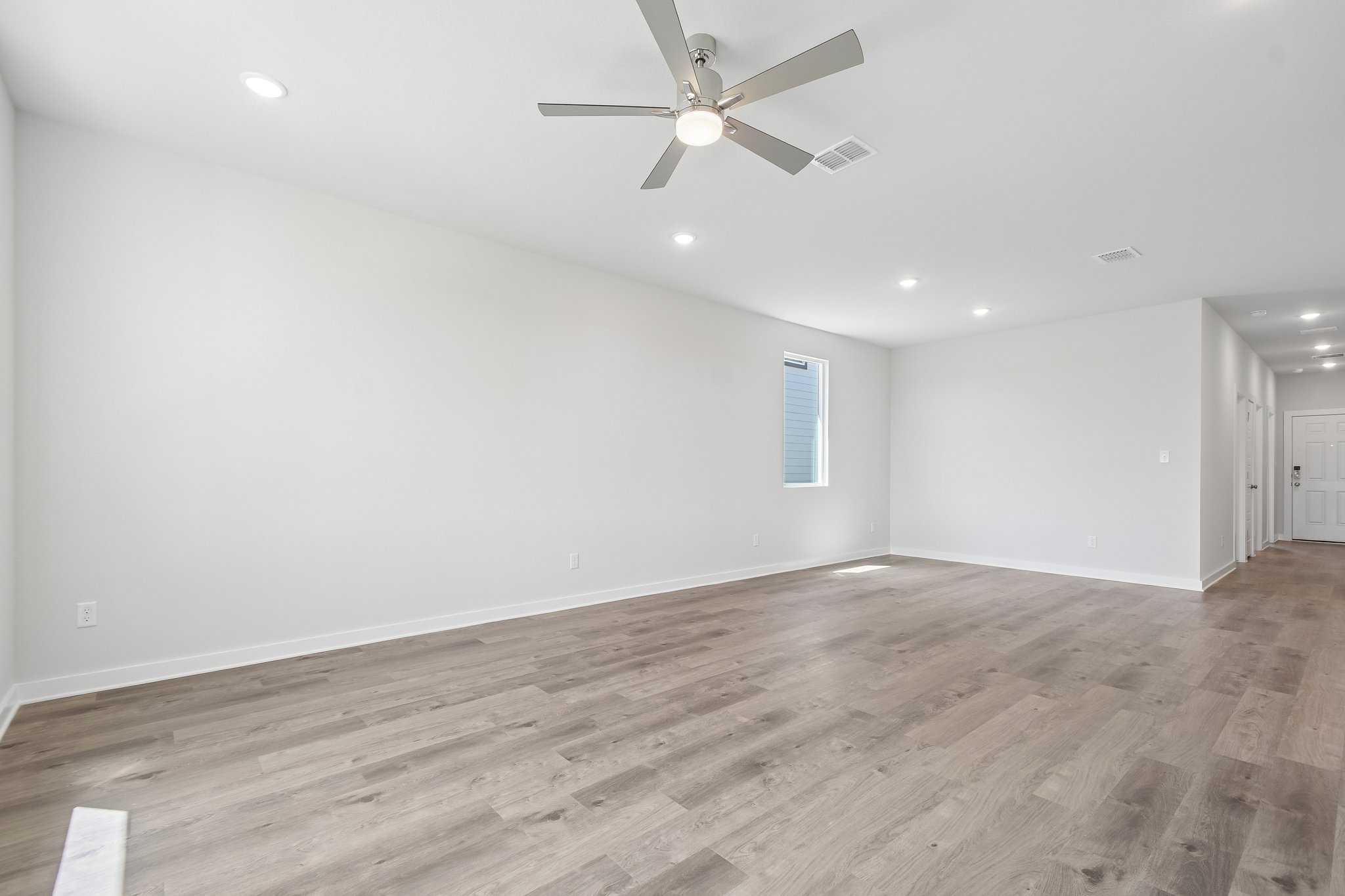 A room with a ceiling fan and wood floor.