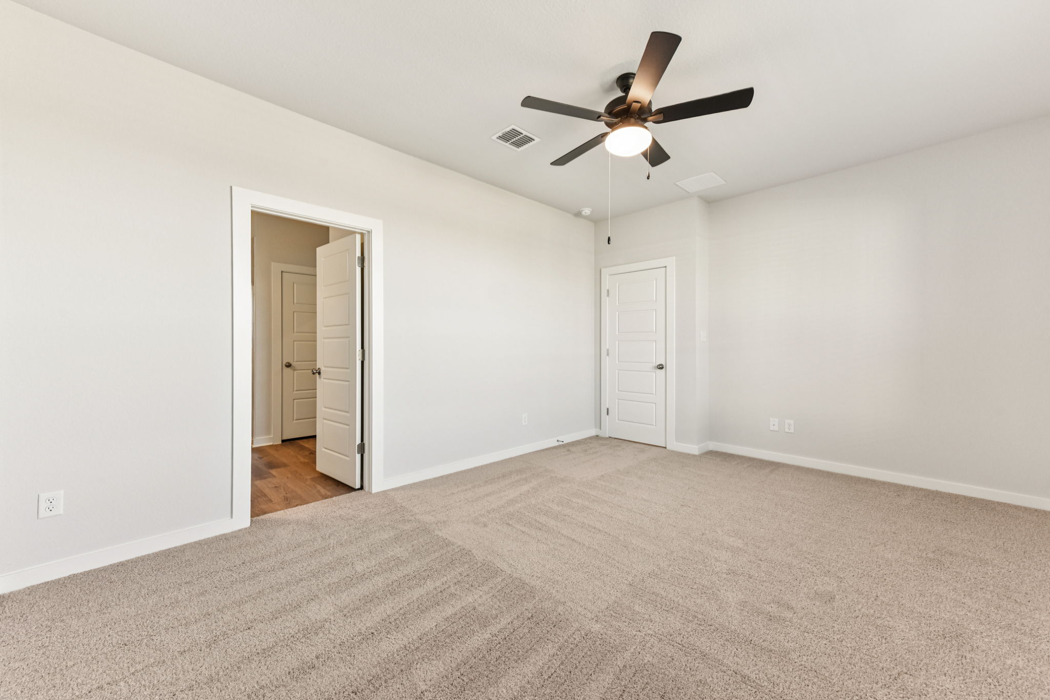 A room with a ceiling fan and a door.