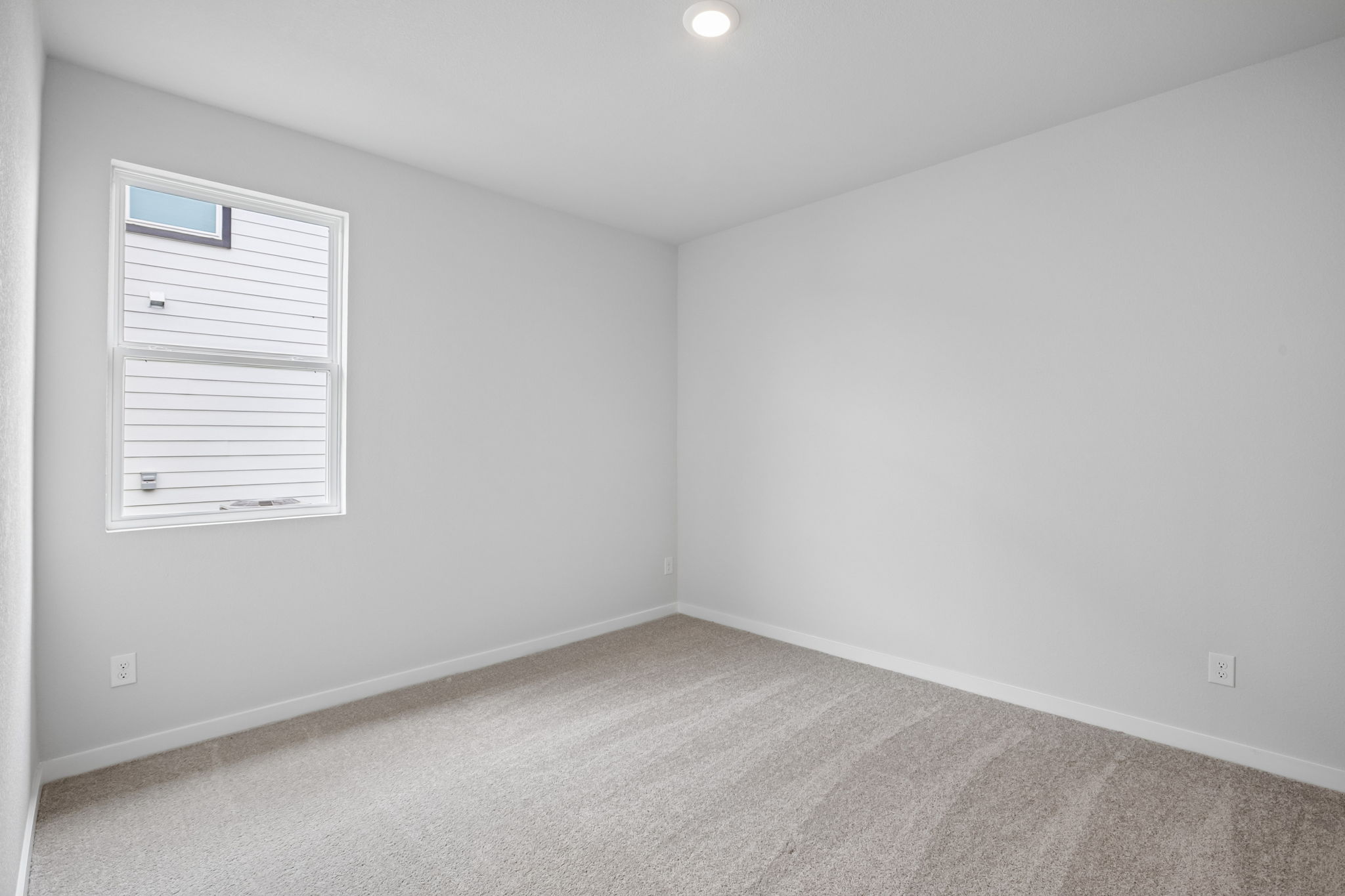 A room with a white wall and a window.