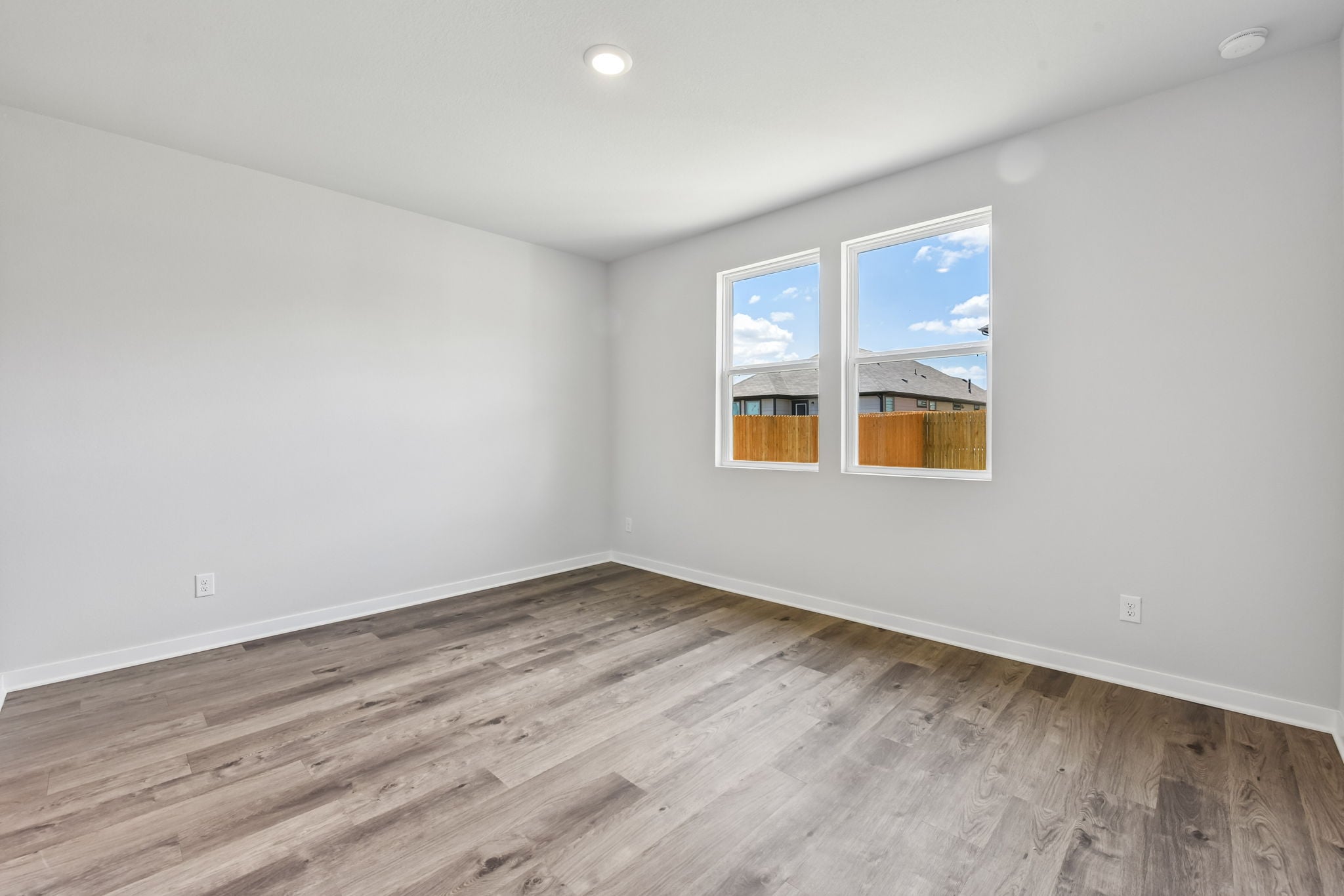 A room with a wood floor and a window with a view of the city.