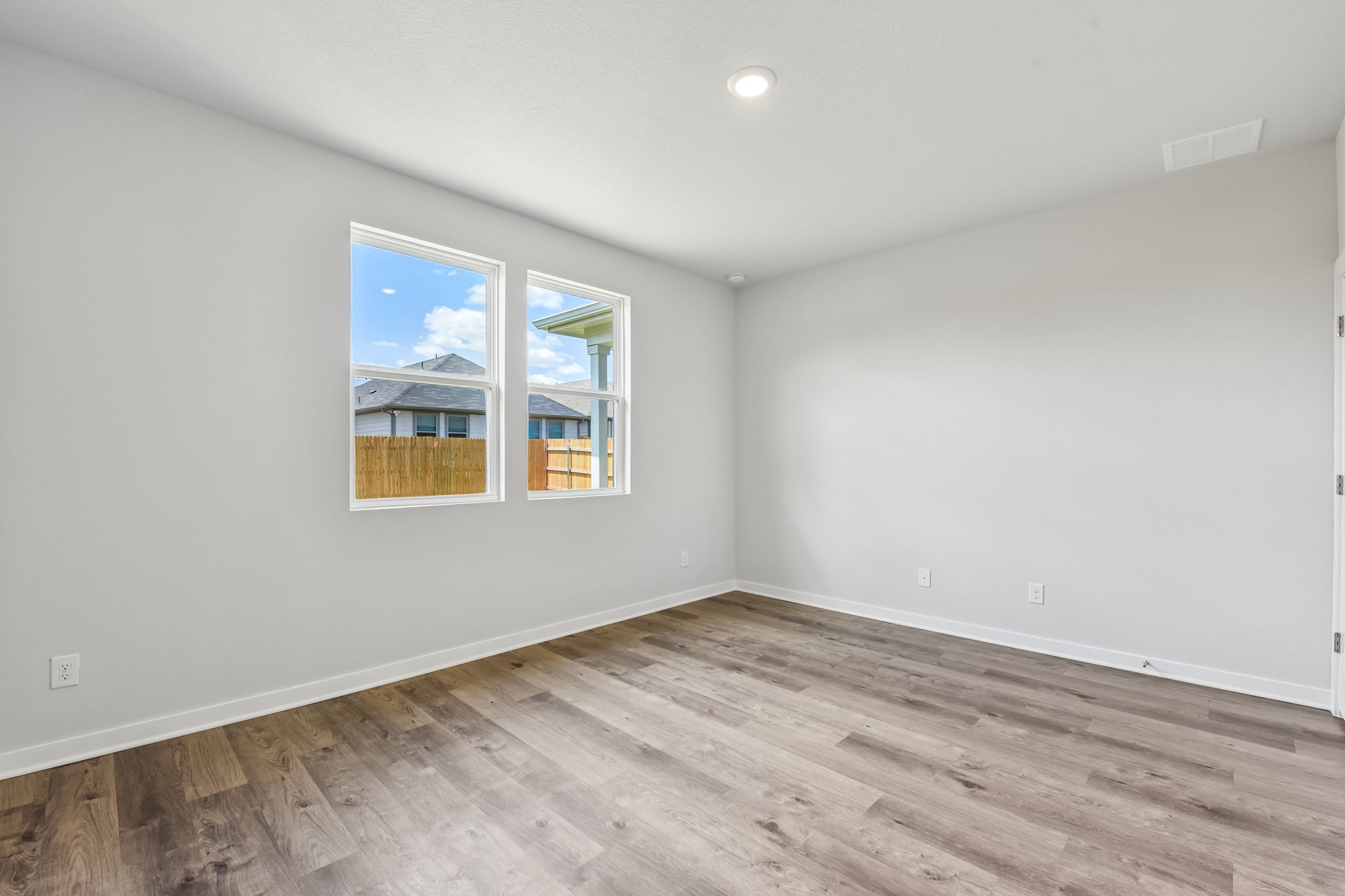 A room with a wood floor and a window with a view of a city.