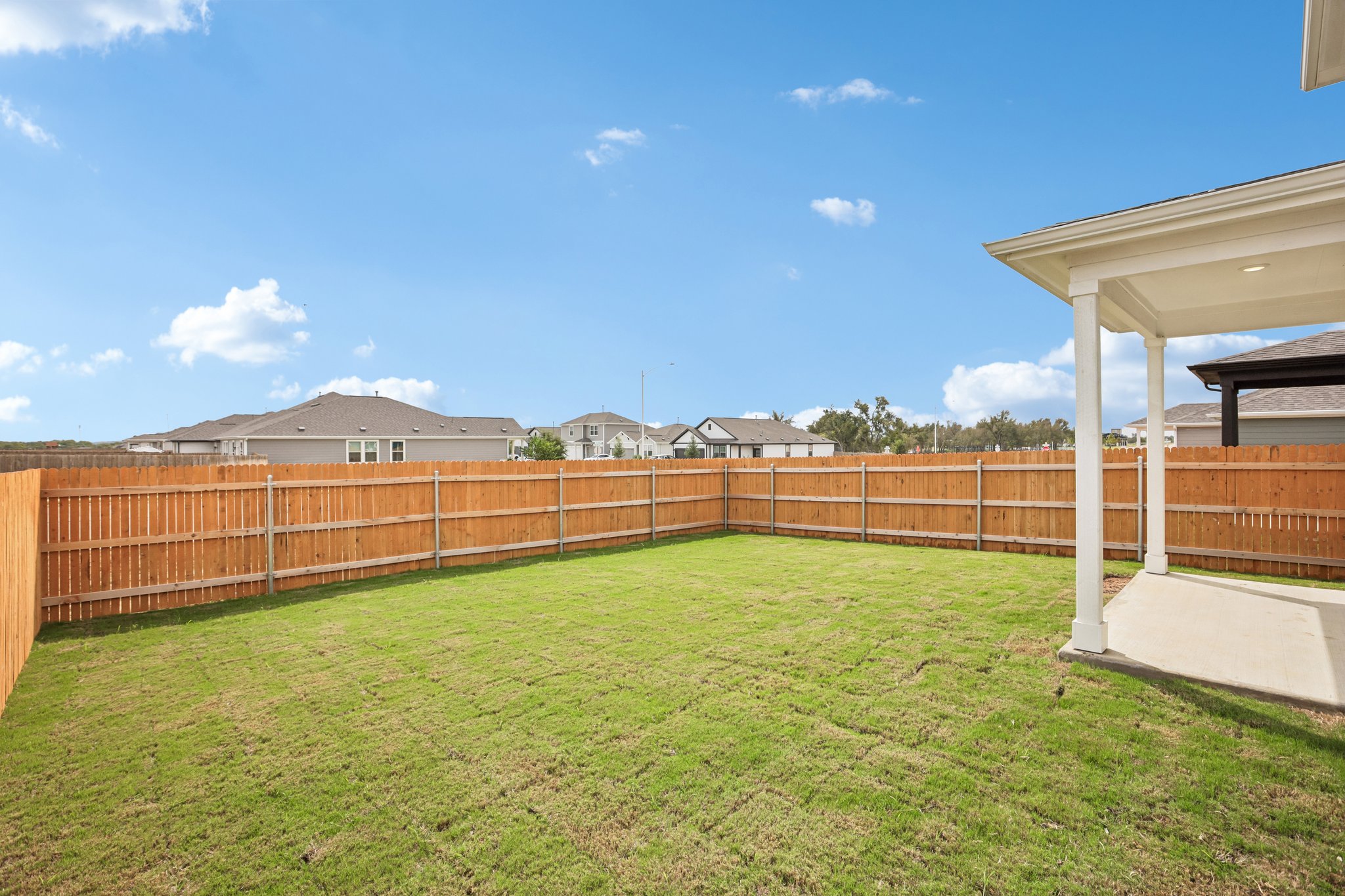 A fenced in yard with a wood fence and a building in the background.