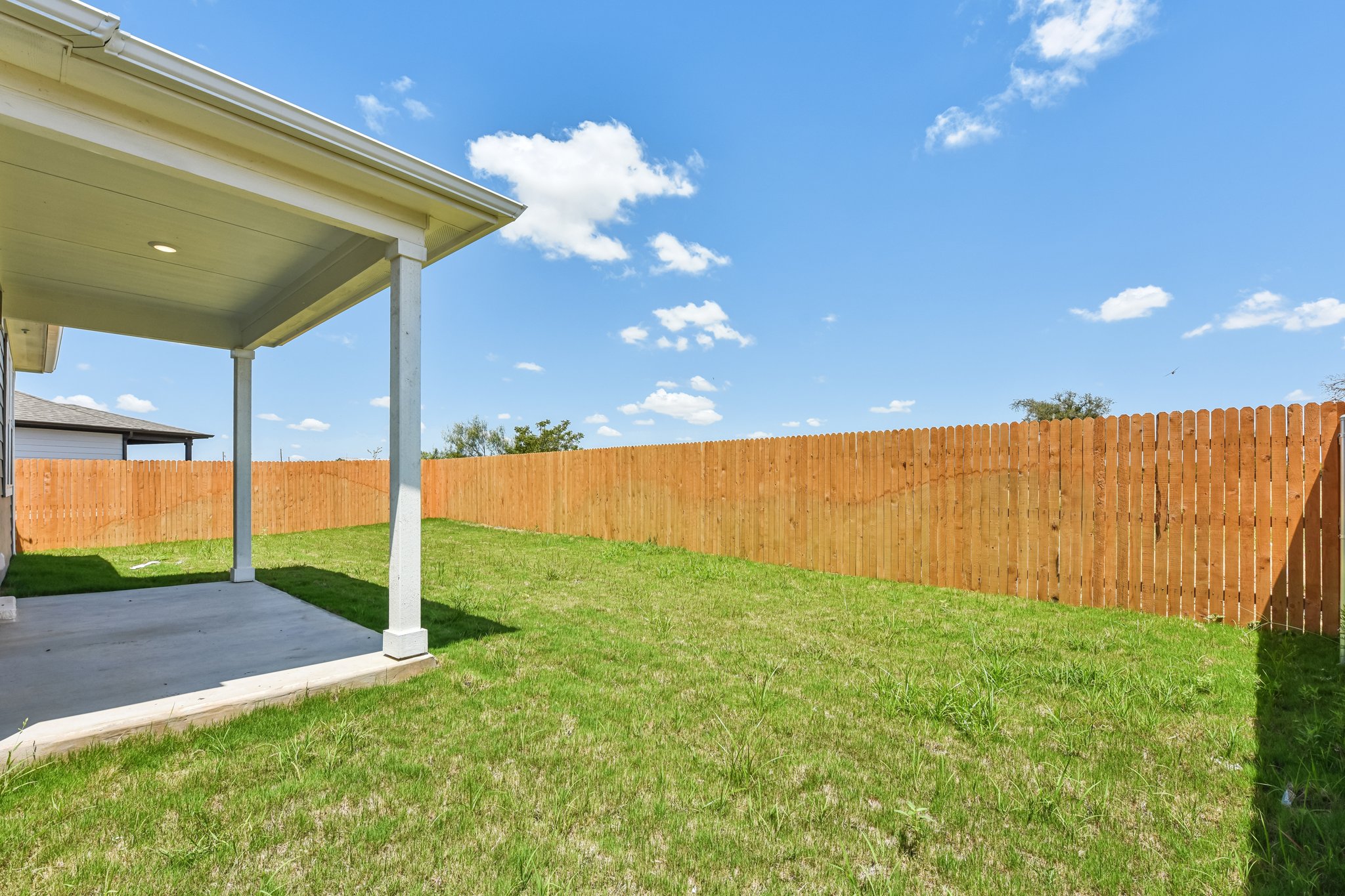 A fenced in yard with a wood fence and a wood building.