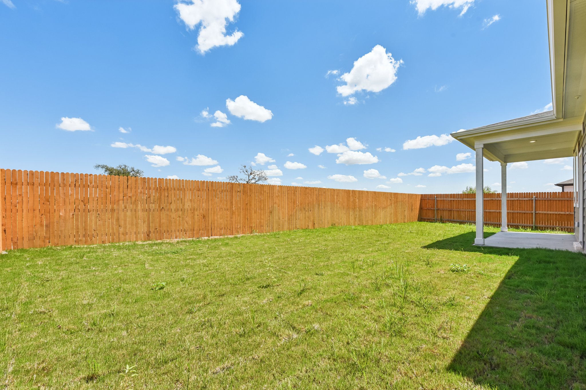 A fenced in yard with a building and a wood fence.