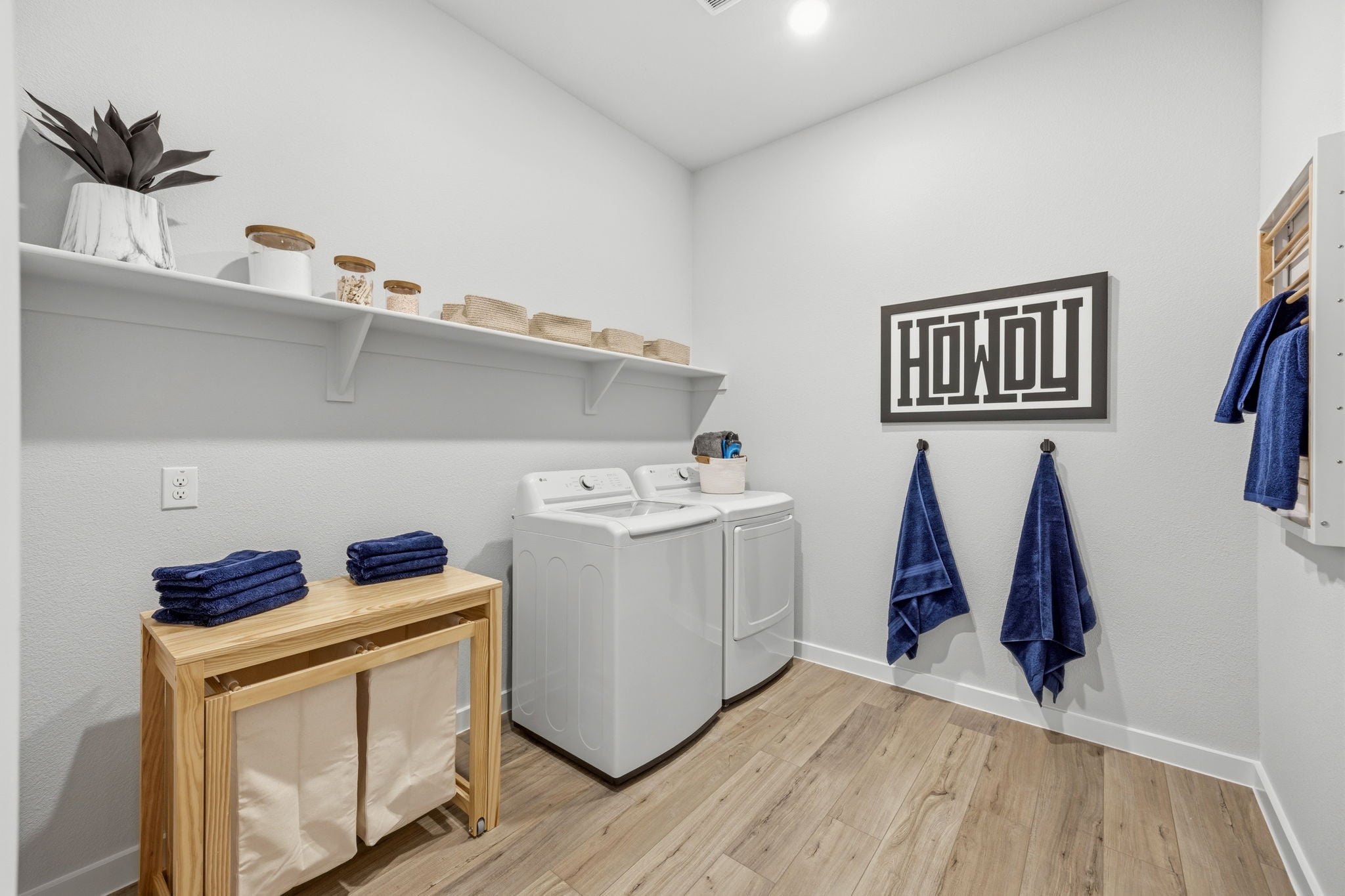 A room with a table and a shelf with clothes on it.
