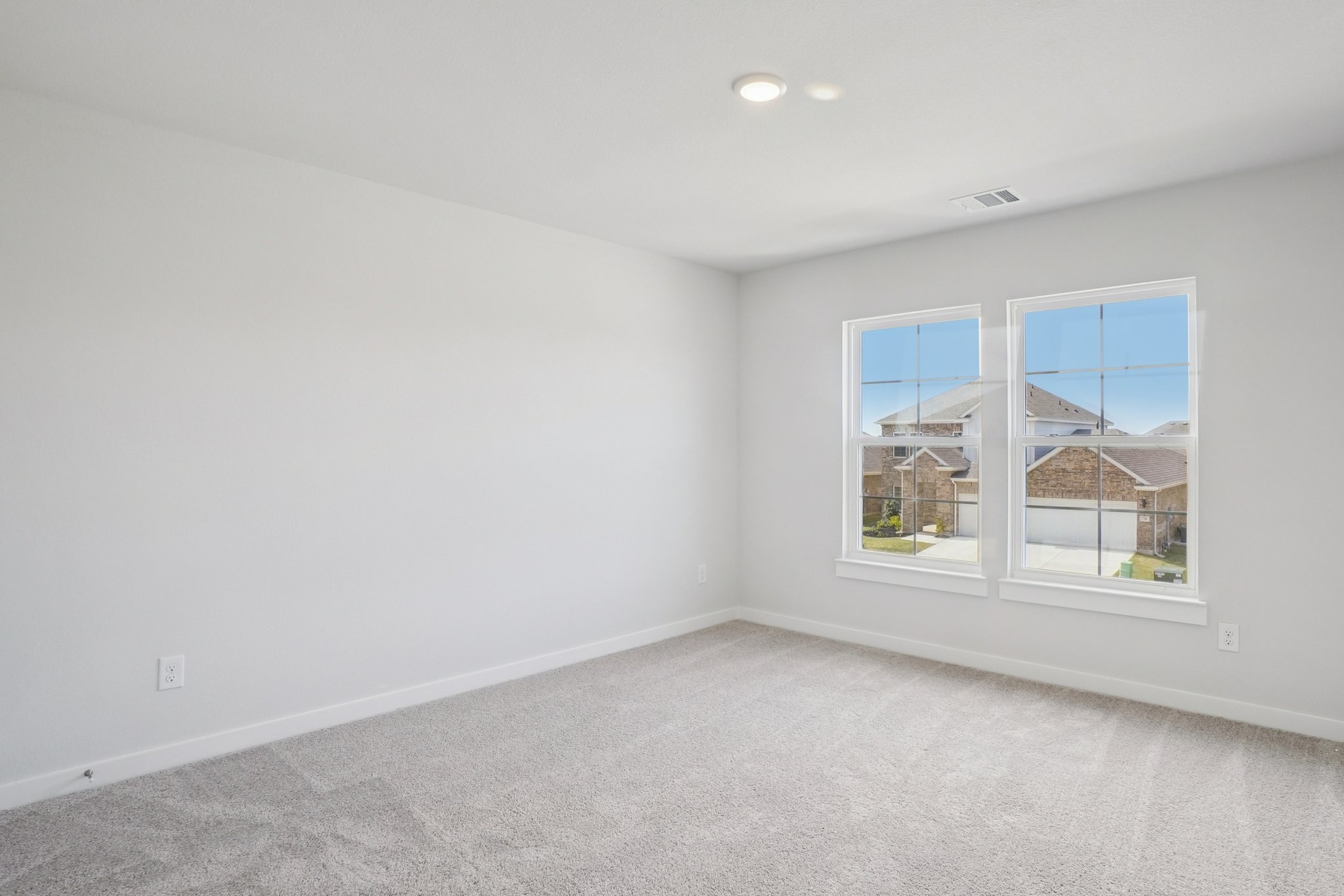 A room with a window and a white wall with a view of a city.