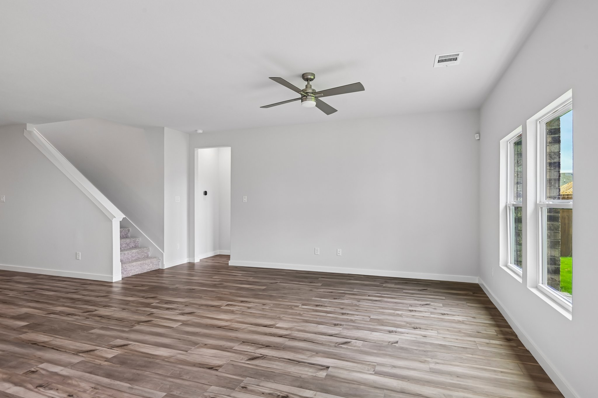 A room with a wood floor and a ceiling fan.